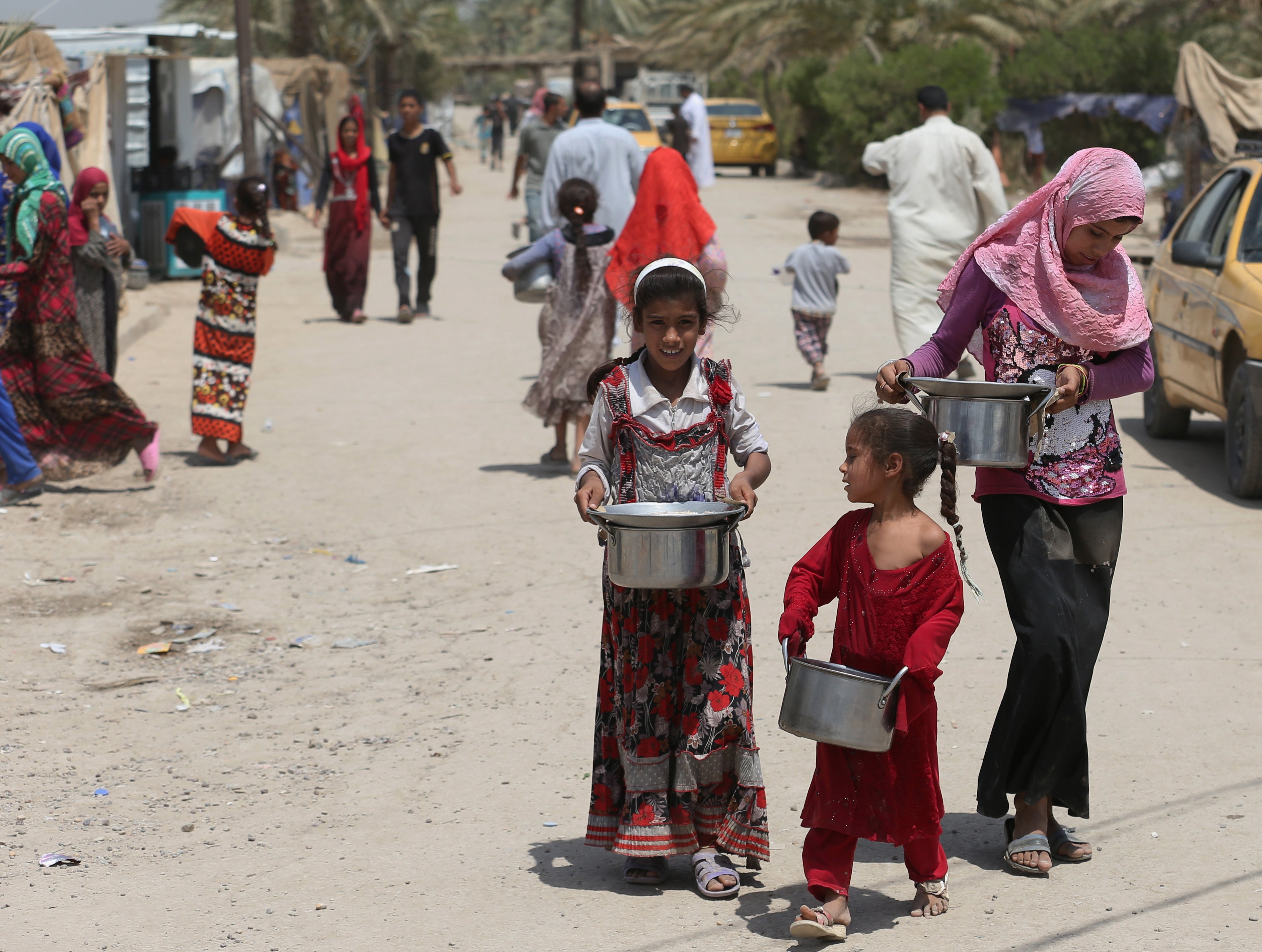 Displaced Iraqis carry donated food at al-Takia refugee camp in Baghdad on July 30, 2015.