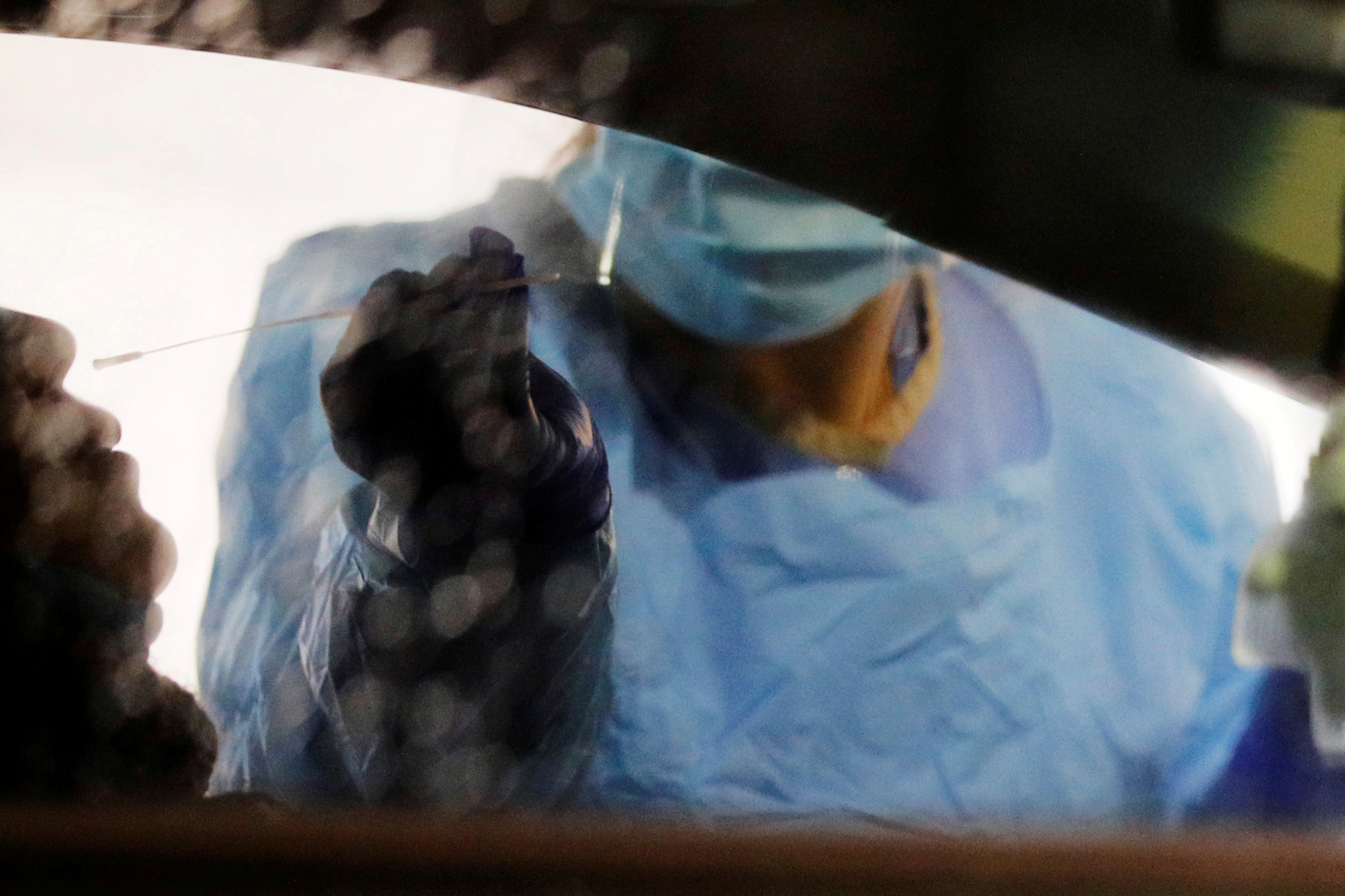 Medical personnel swab a driver’s nose at a drive-through testing site for coronavirus for employees at UW Medical Center - Northwest in Seattle on March 13, 2020.