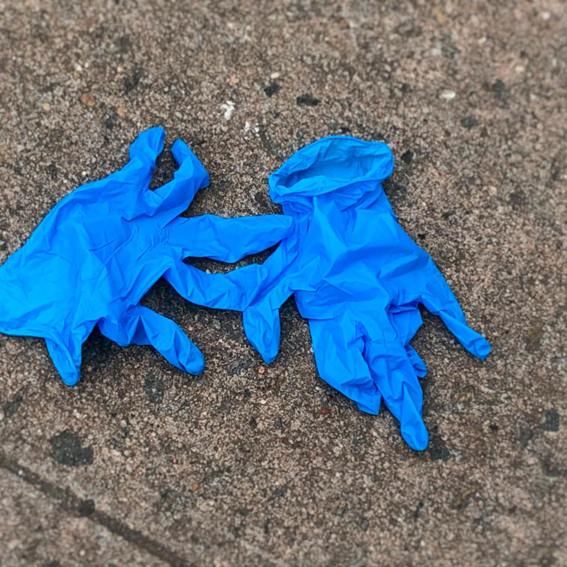 Medical gloves discarded on sidewalk.