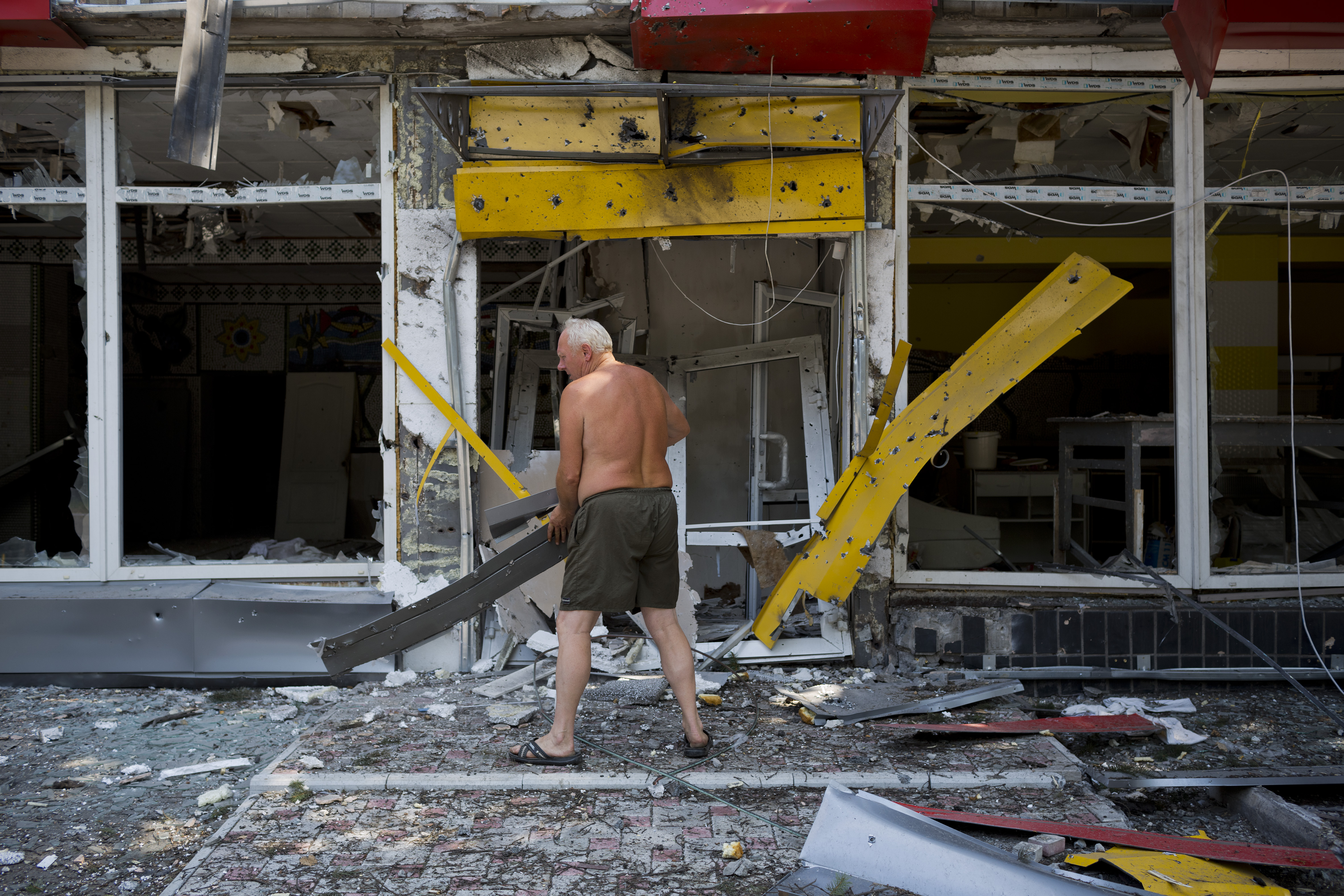 A man clears debris as the Ukrainian army retakes a village from pro-Russian rebels onAugust 13, 2014 in Uglegorsk. Ukraine.