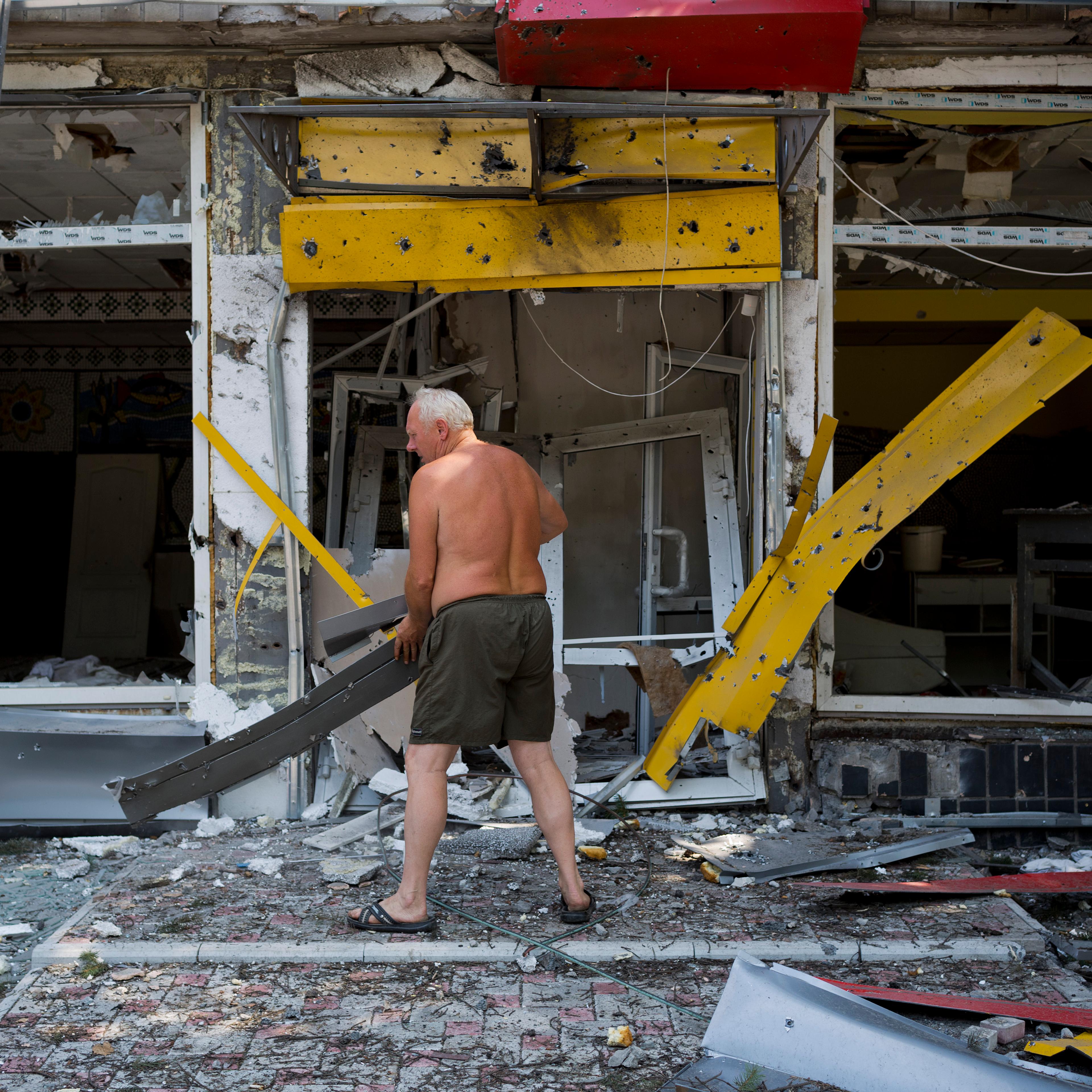 A man clears debris as the Ukrainian army retakes a village from pro-Russian rebels onAugust 13, 2014 in Uglegorsk. Ukraine.