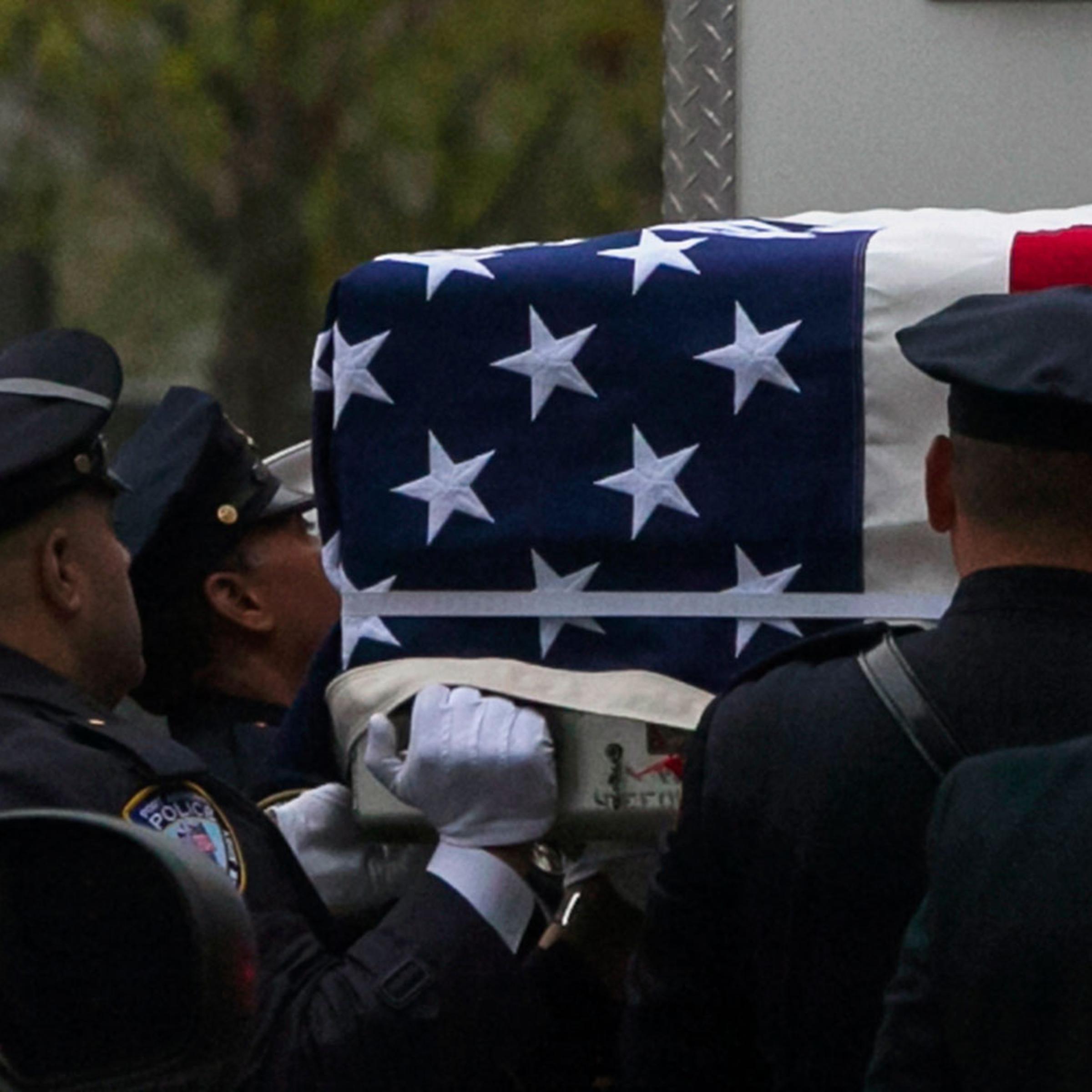 Emergency personnel carry a casket draped with a U.S. flag during the ceremonial transfer of the 9/11 unidentified remains to the OCME repository at the World Trade Center site, in New York