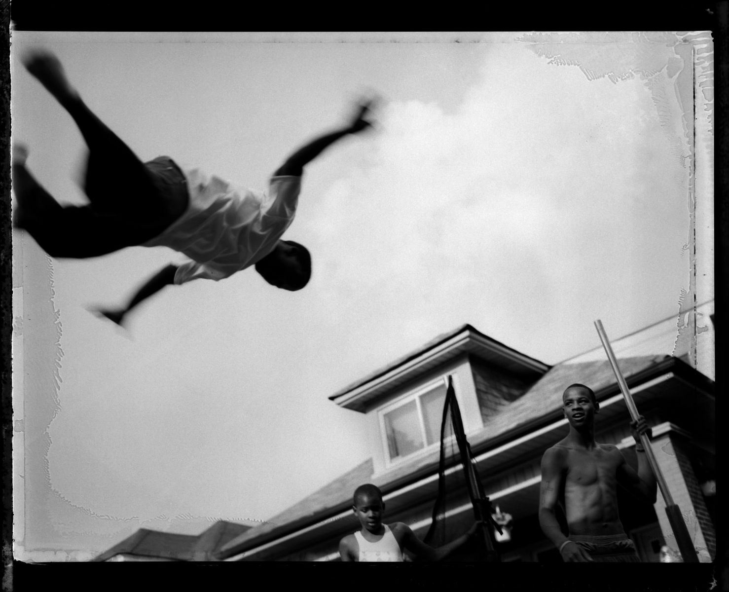 A young man jumps on a trampoline at a summer block club party, Auburn-Gresham, 2009. 