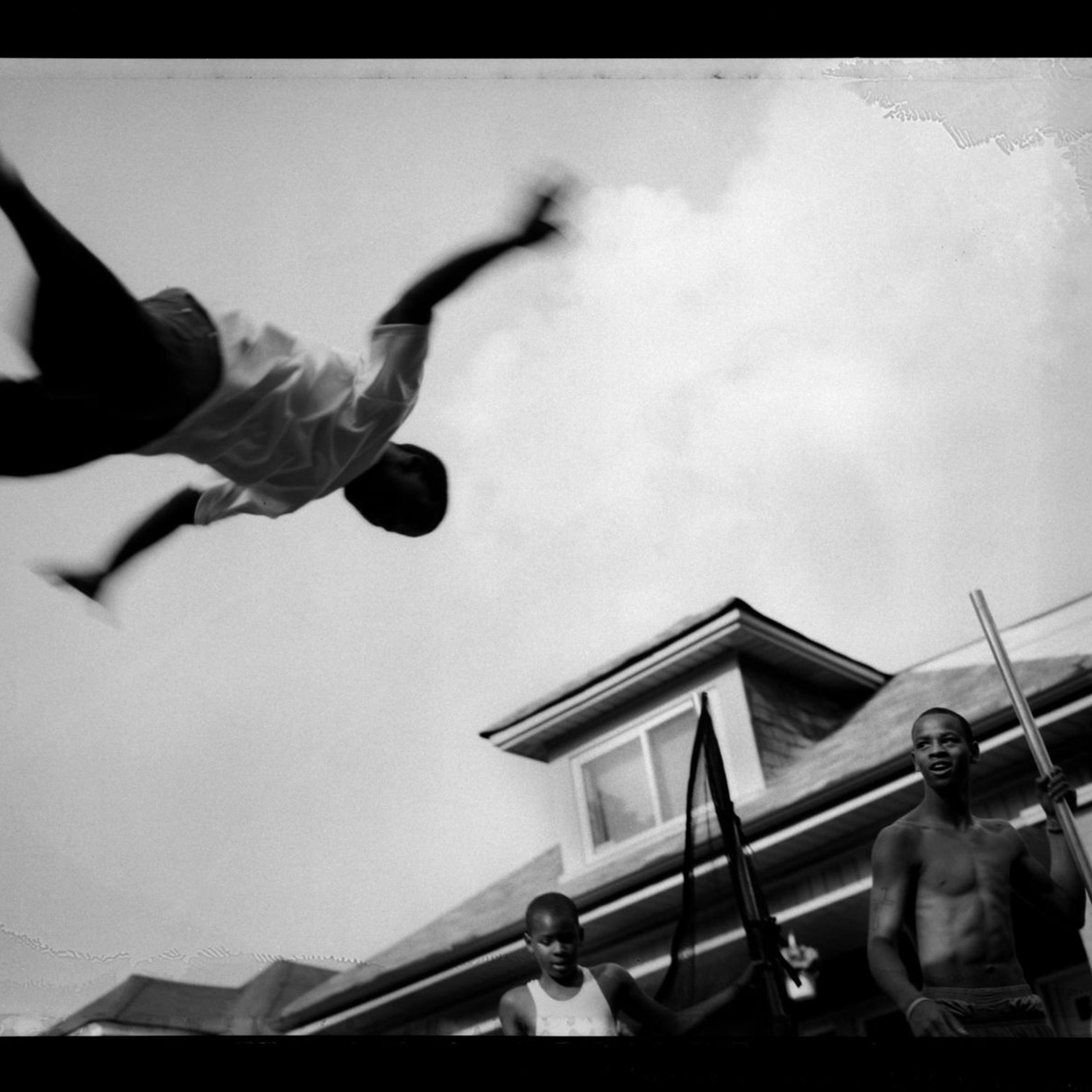 A young man jumps on a trampoline at a summer block club party, Auburn-Gresham, 2009.