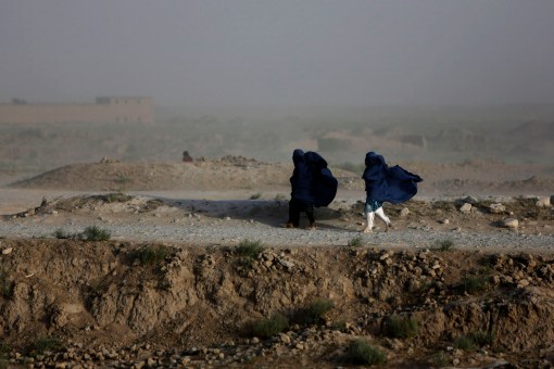 Women walk on a windy day outside Kabul