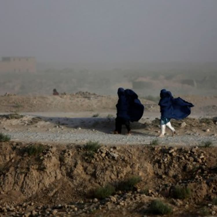 Women walk on a windy day outside Kabul
