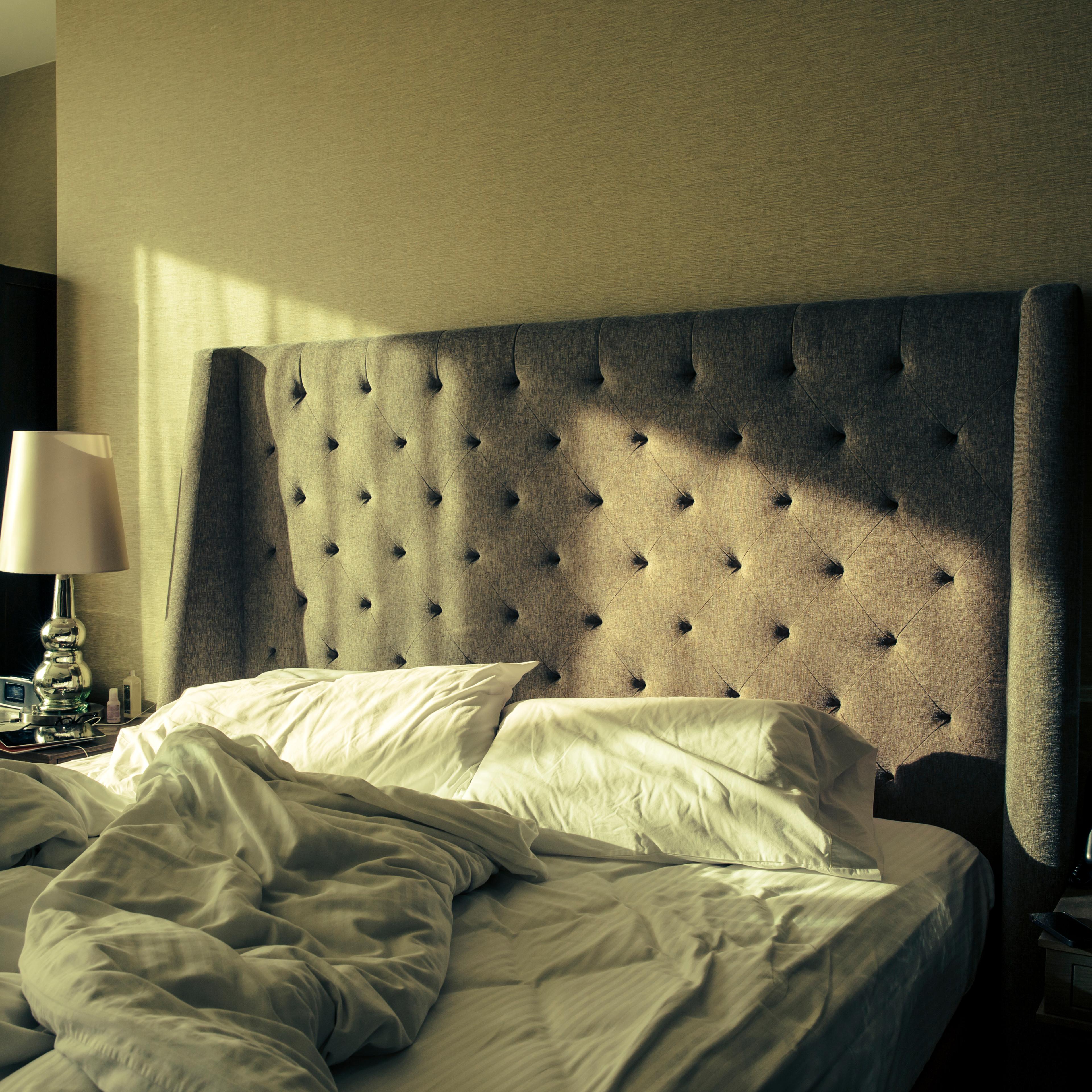 Window shining light onto unmade bed