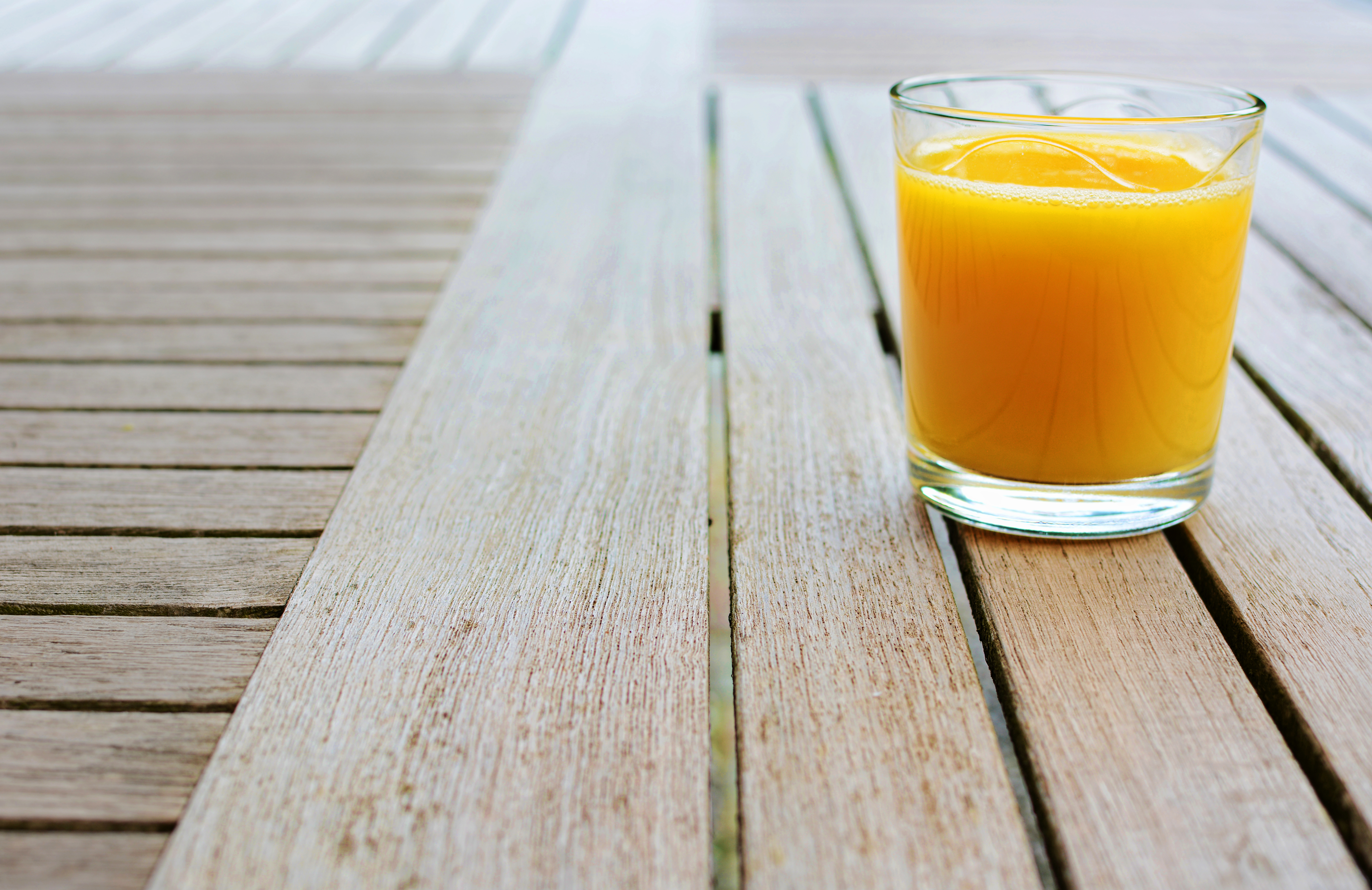 Glass of orange juice standing on wood table
