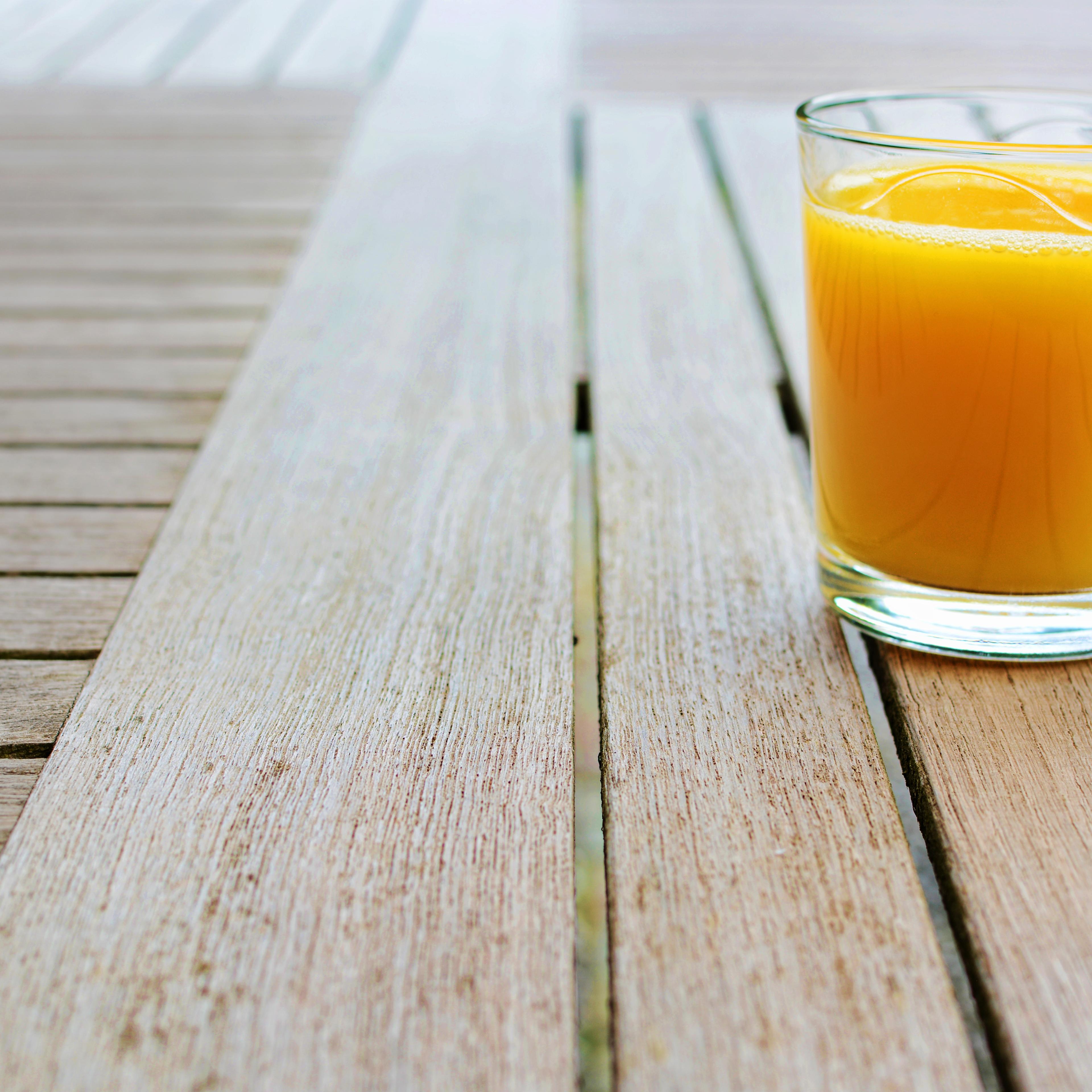 Glass of orange juice standing on wood table