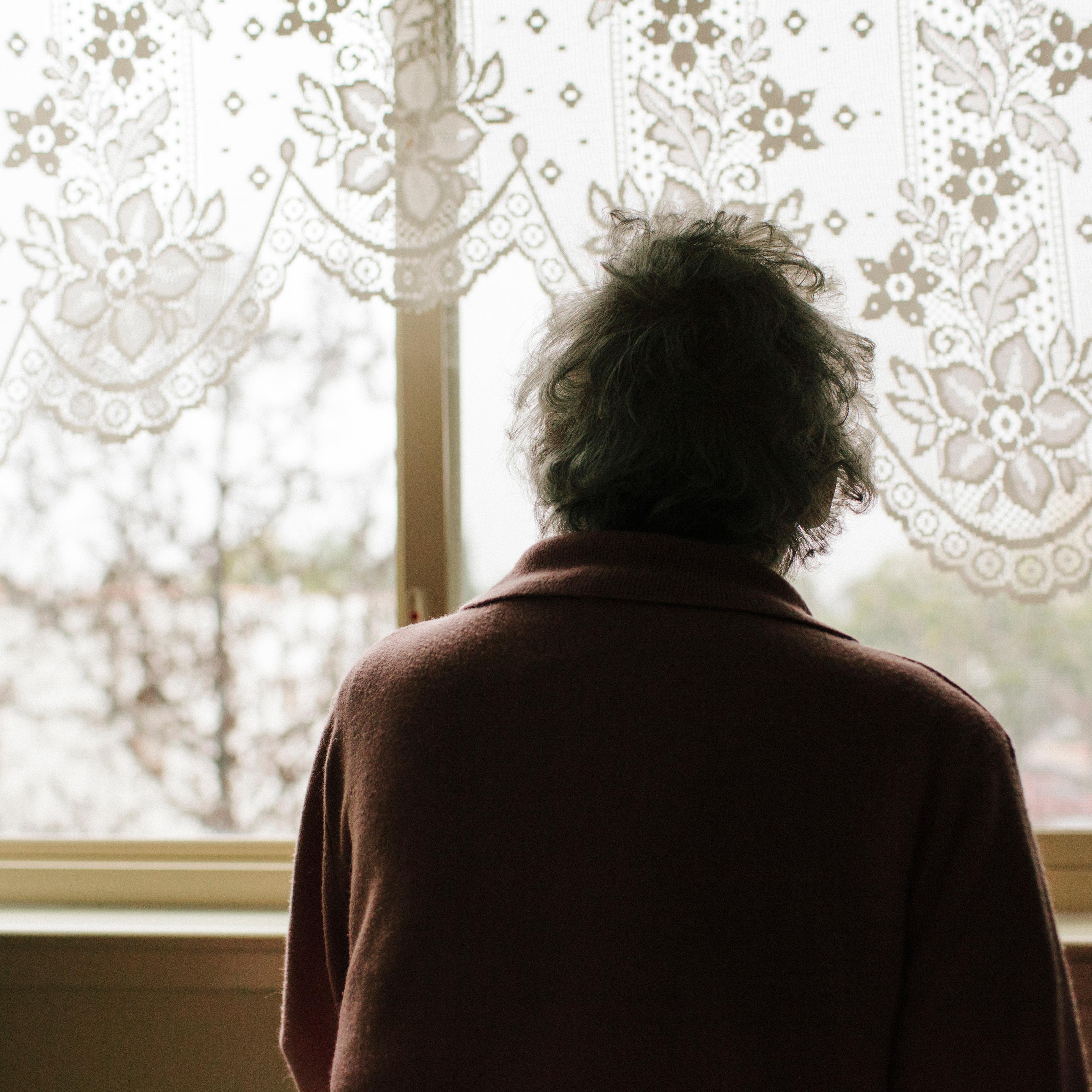 Pensive mixed race older woman looking out window