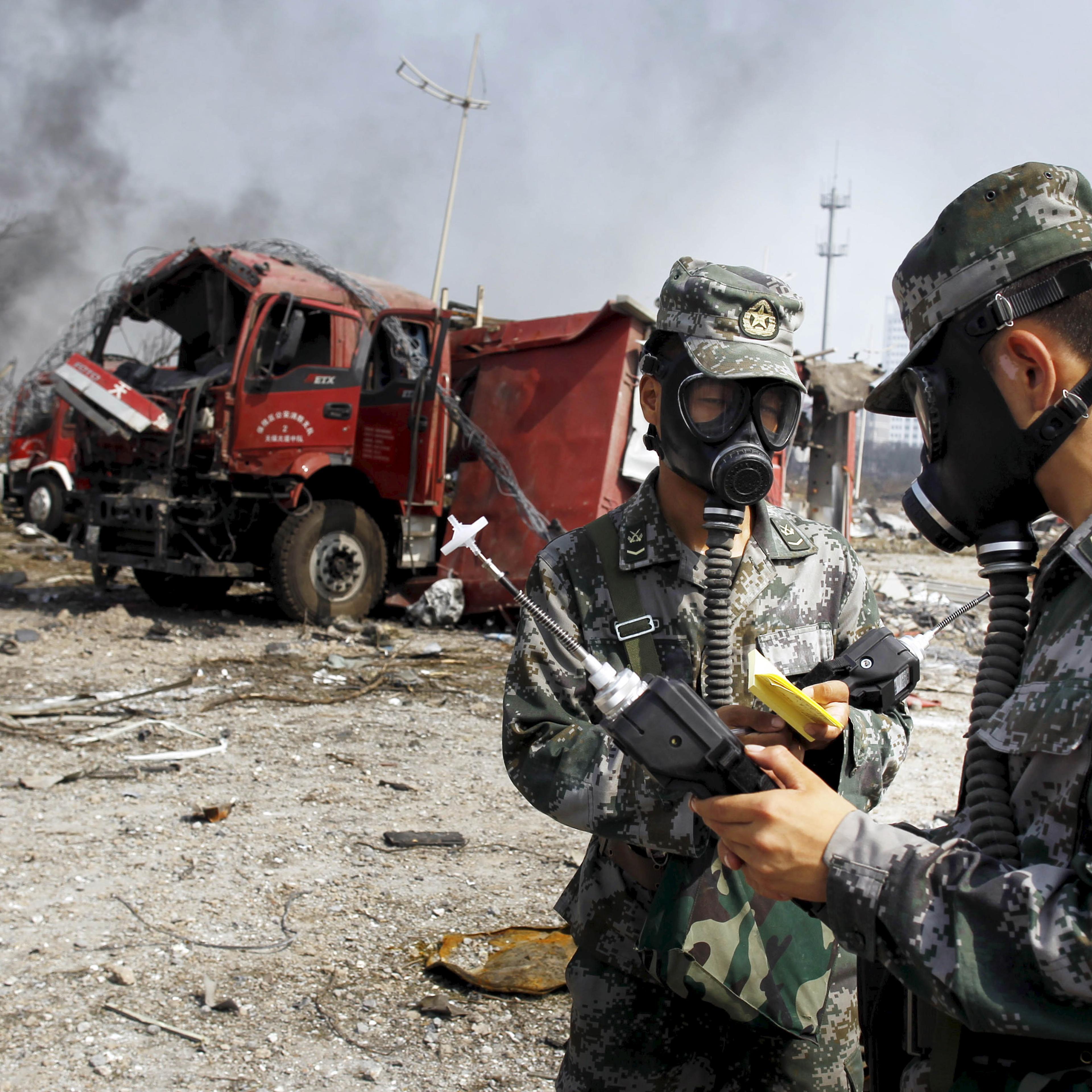 Soldiers of the People's Liberation Army anti-chemical warfare corps work next to a damaged firefighting vehicle at the site of Wednesday night's explosions at Binhai new district