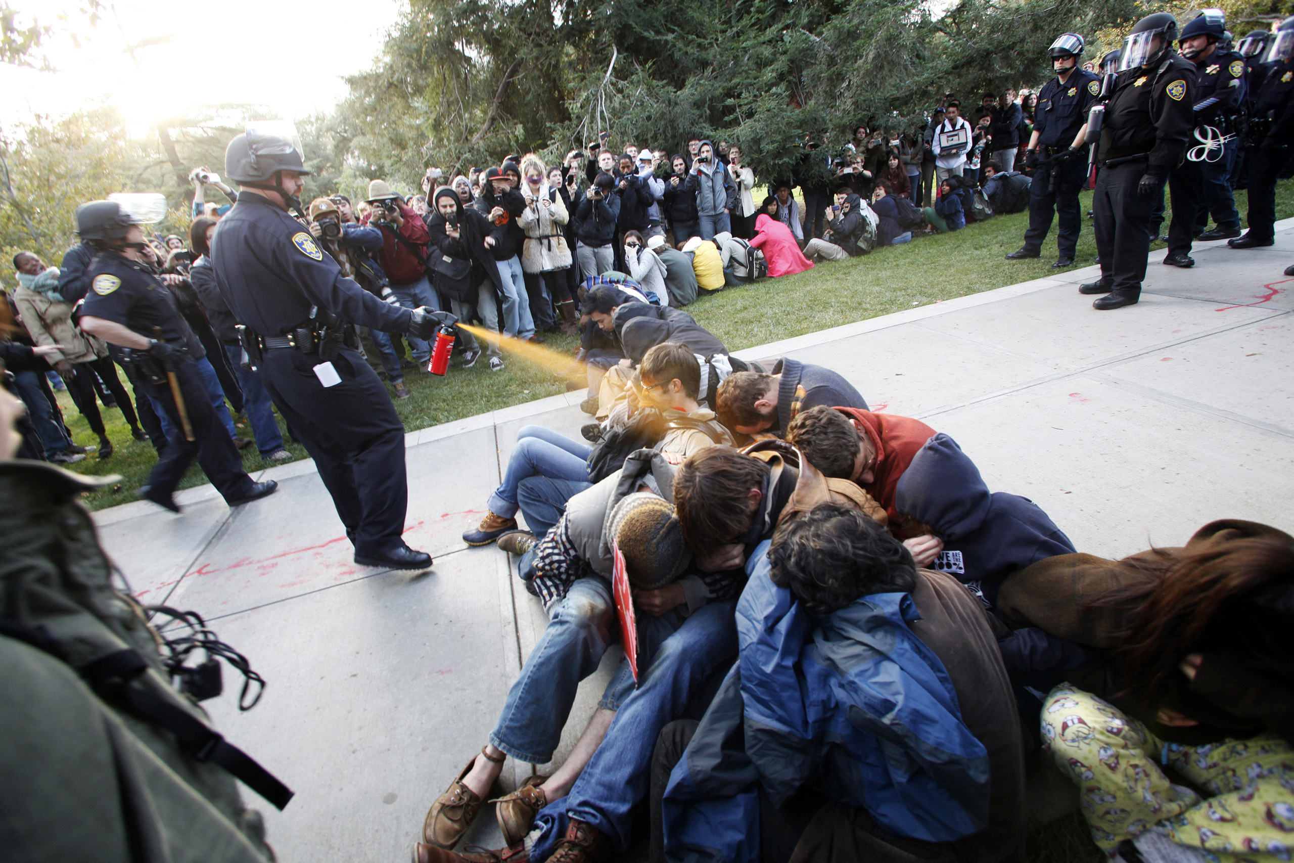 In this Nov. 18, 2011, file photo, University of California, Davis Police Lt. John Pike uses pepper spray to move Occupy UC Davis protesters while blocking their exit from the school's quad in Davis, Calif. The school reportedly paid image consultants at