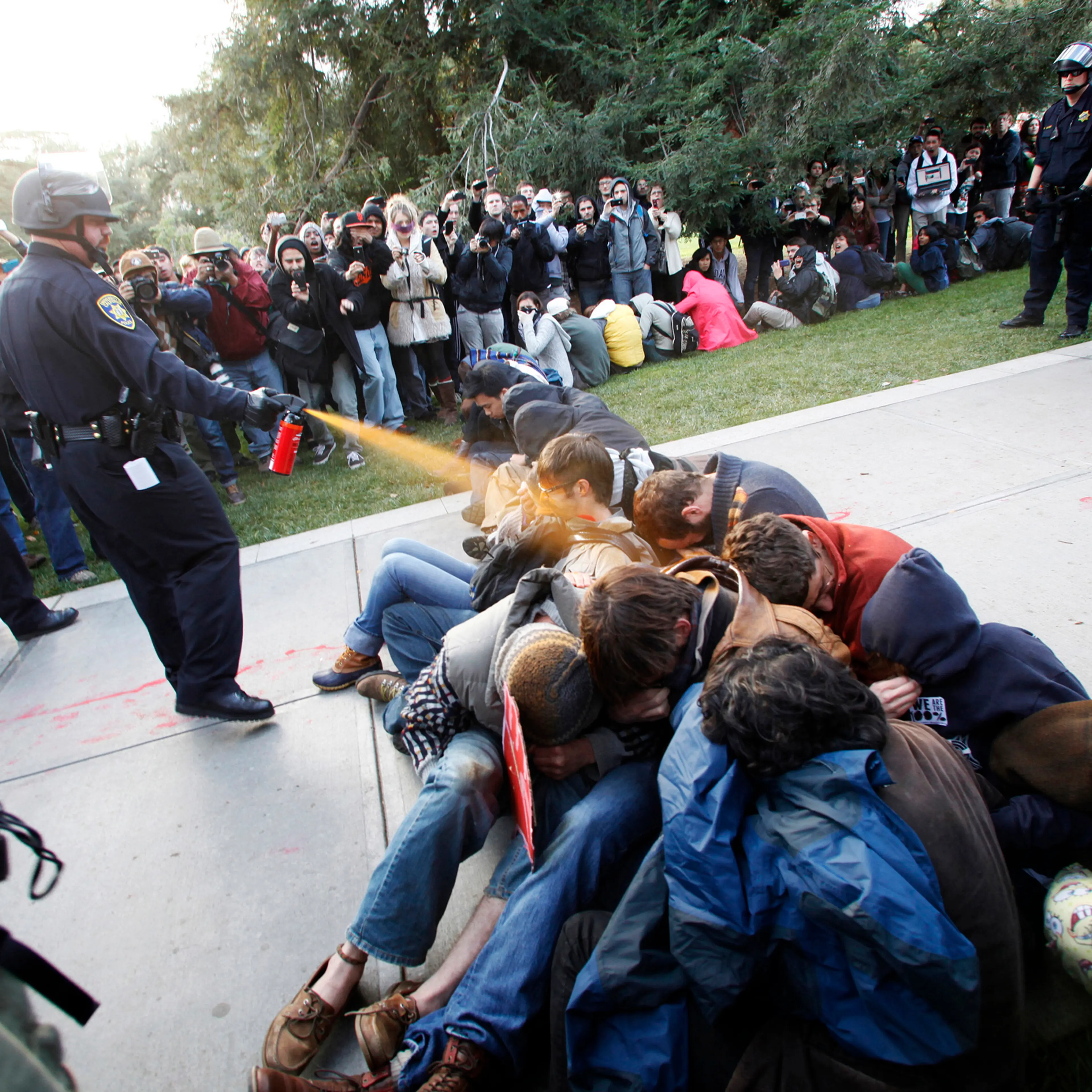 In this Nov. 18, 2011, file photo, University of California, Davis Police Lt. John Pike uses pepper spray to move Occupy UC Davis protesters while blocking their exit from the school's quad in Davis, Calif. The school reportedly paid image consultants at