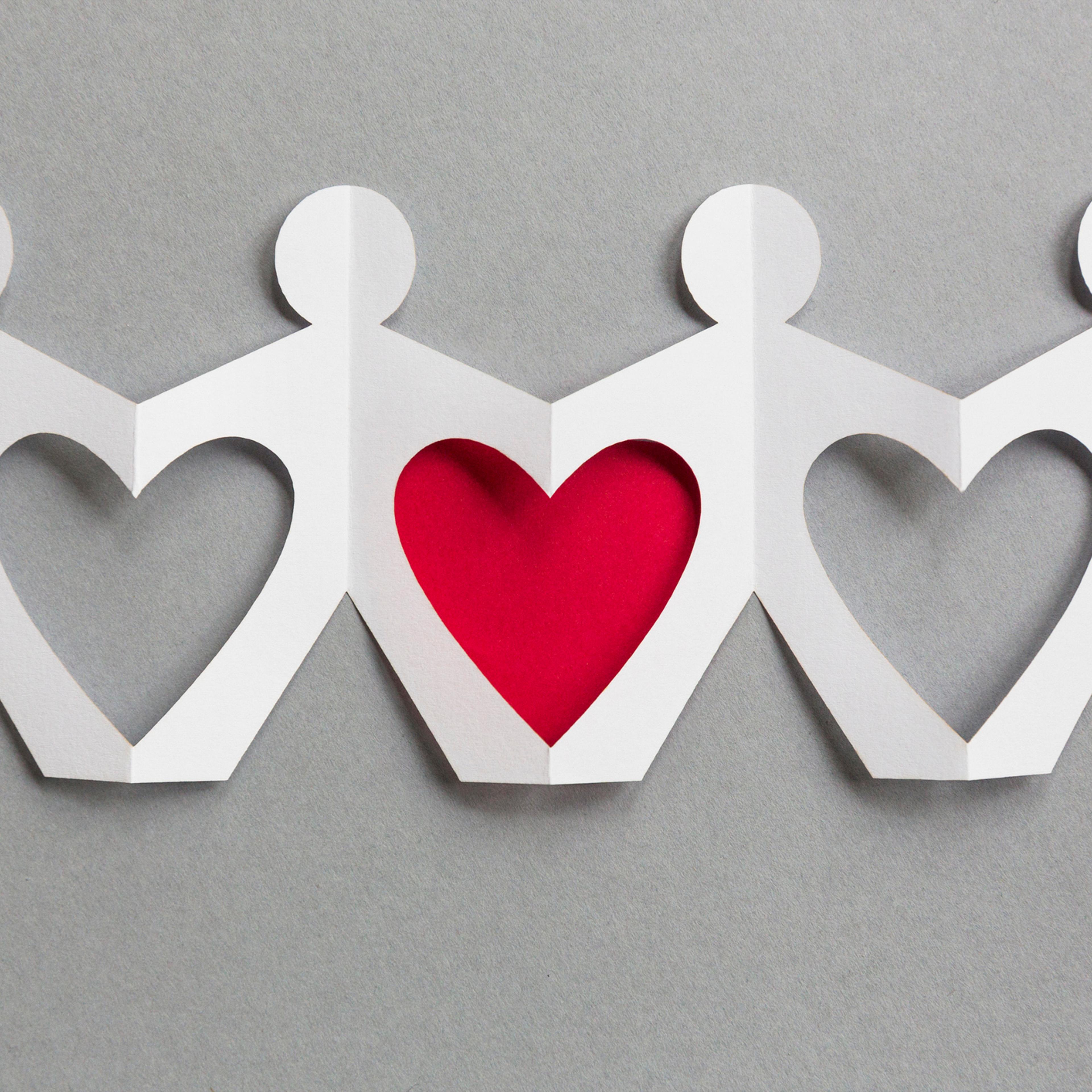 Line of paper cut-out figures forming heart shapes