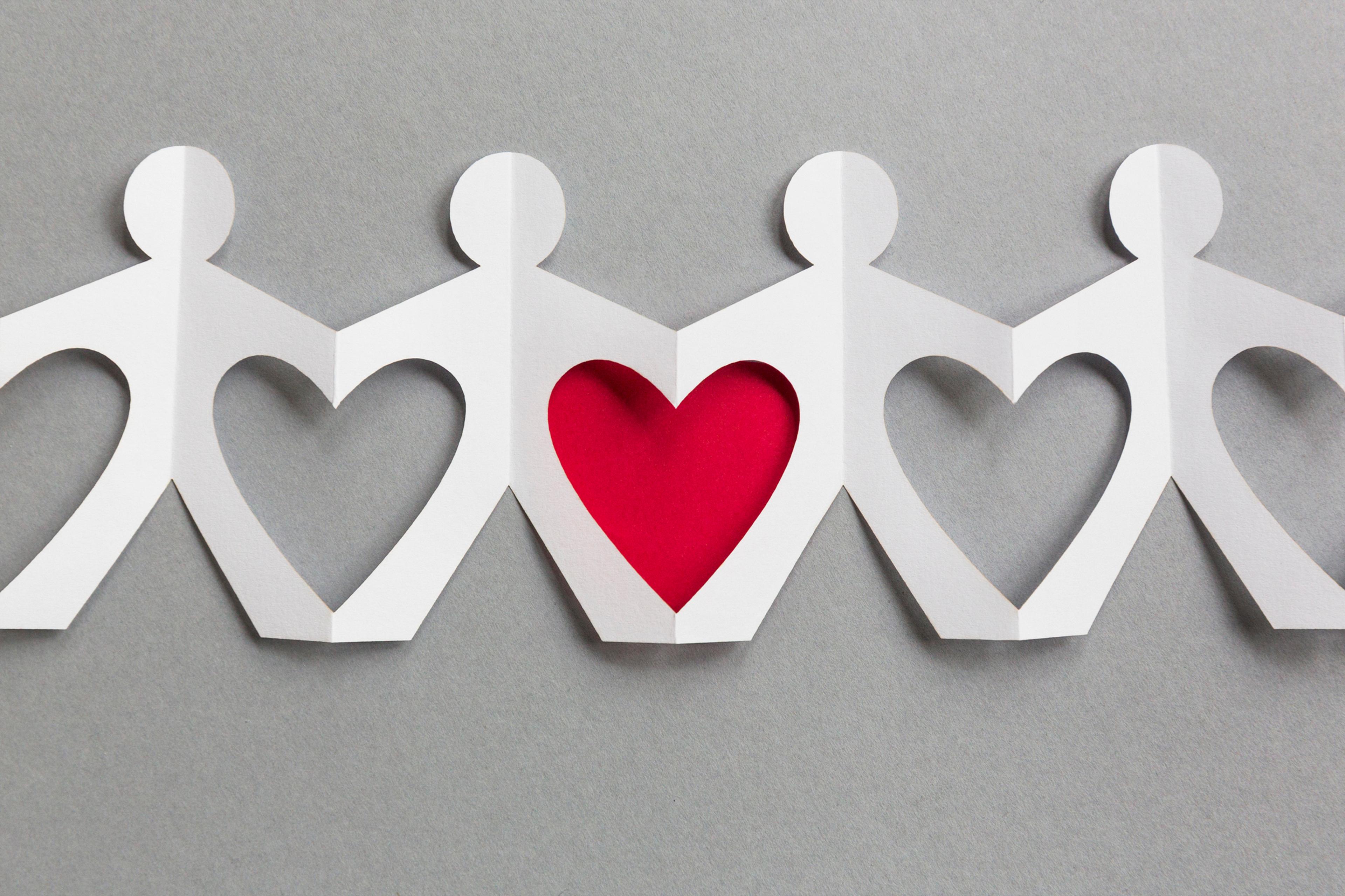 Line of paper cut-out figures forming heart shapes