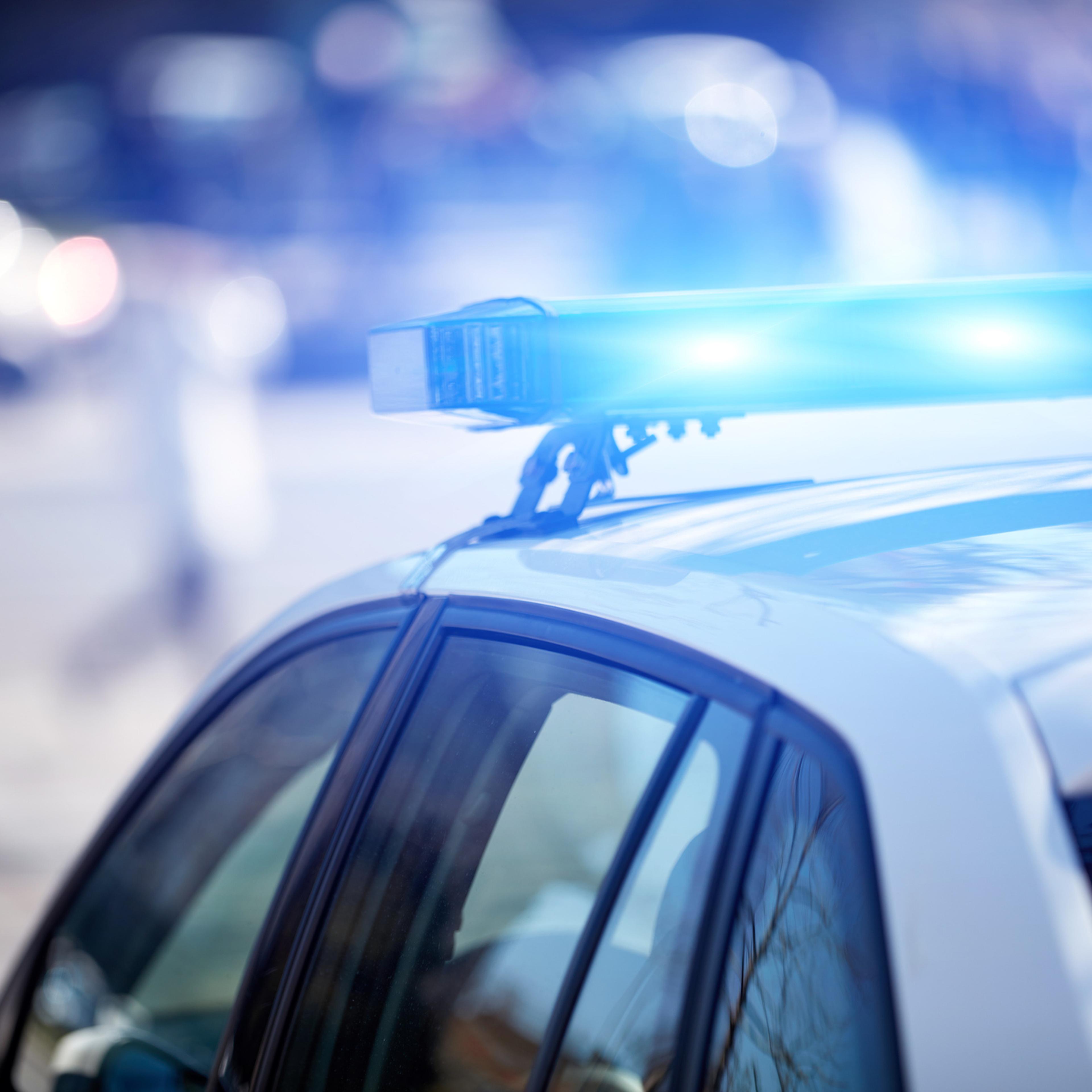 Police car with blue lights on the crime scene in traffic urban environment.