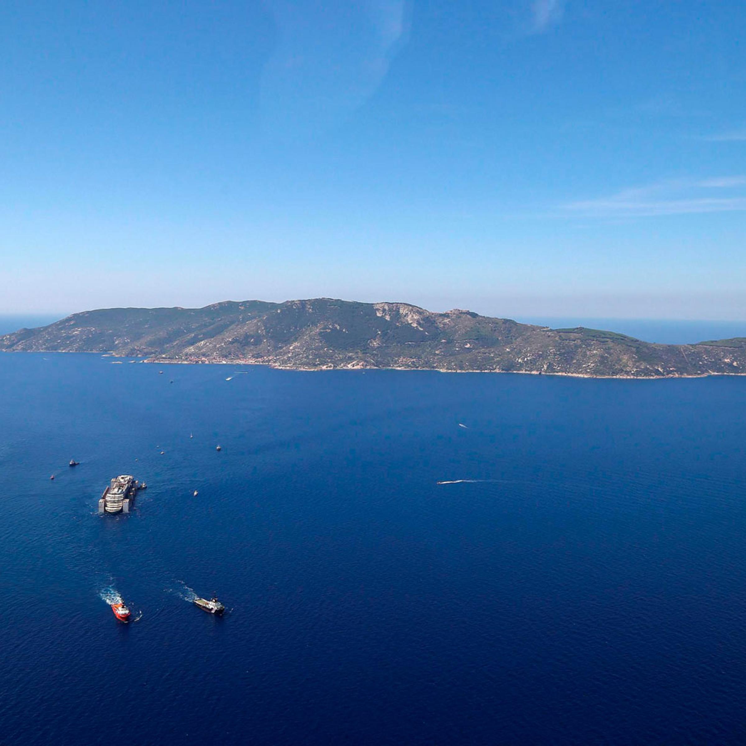 An aerial photo of the wrecked Italian cruise liner the Costa Concordia as it is towed on its final journey to the port of Genoa, Italy from Giglio Island, Italy 240 kilometers away on July 23, 2014.
