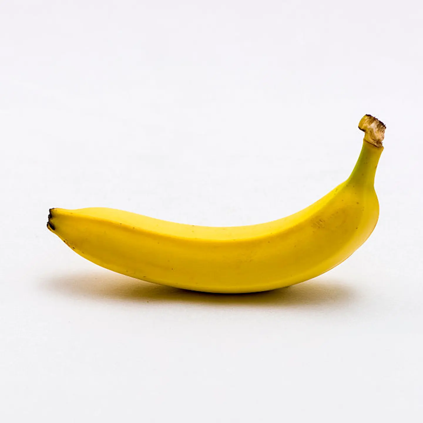 A yellow banana (Musa), displayed on a white table