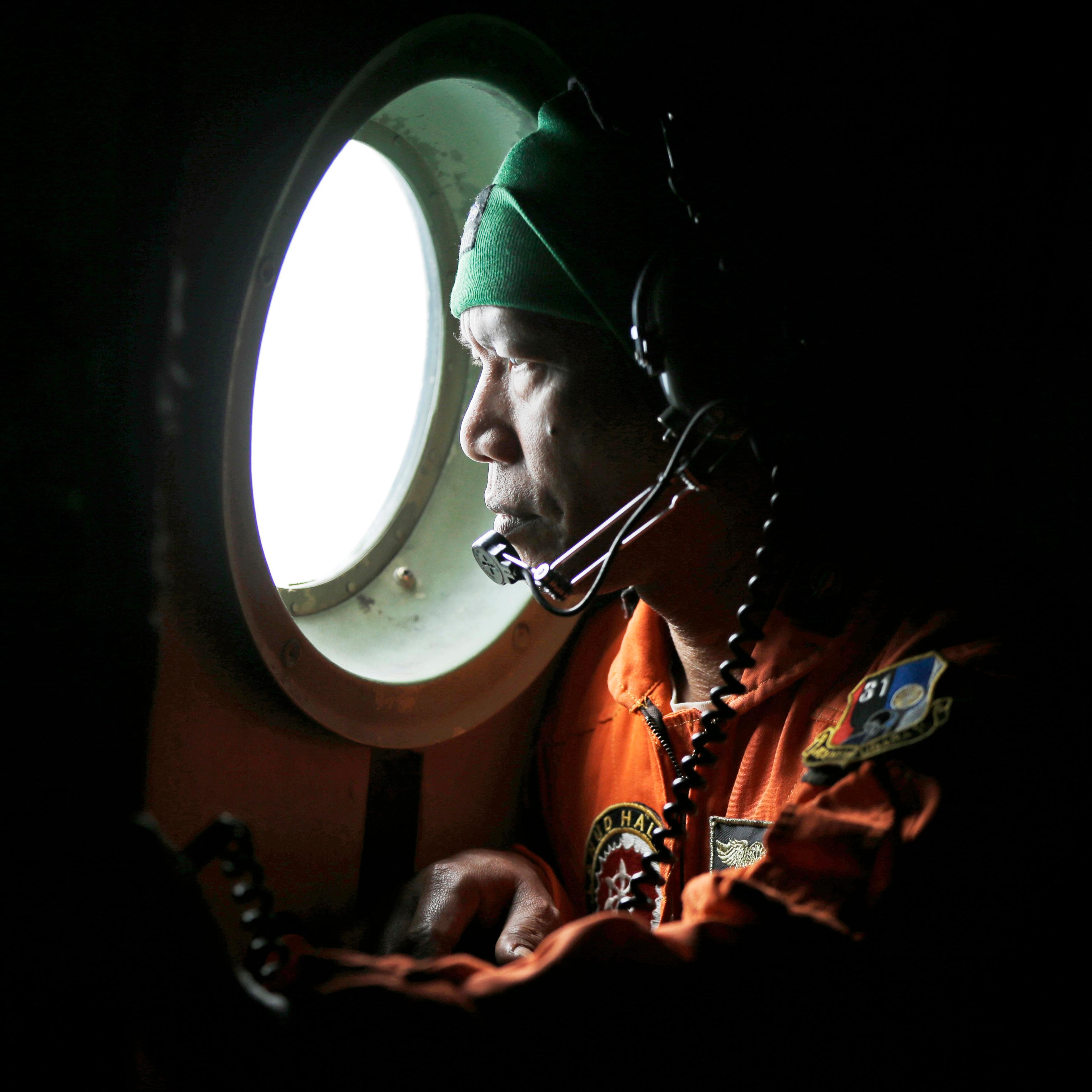 A crew of an Indonesian Air Force C-130 airplane of the 31st Air Squadron looks out of the window during a search operation for the missing AirAsia flight 8501 jetliner over the waters of Karimata Strait in Indonesia on Dec. 29, 2014.