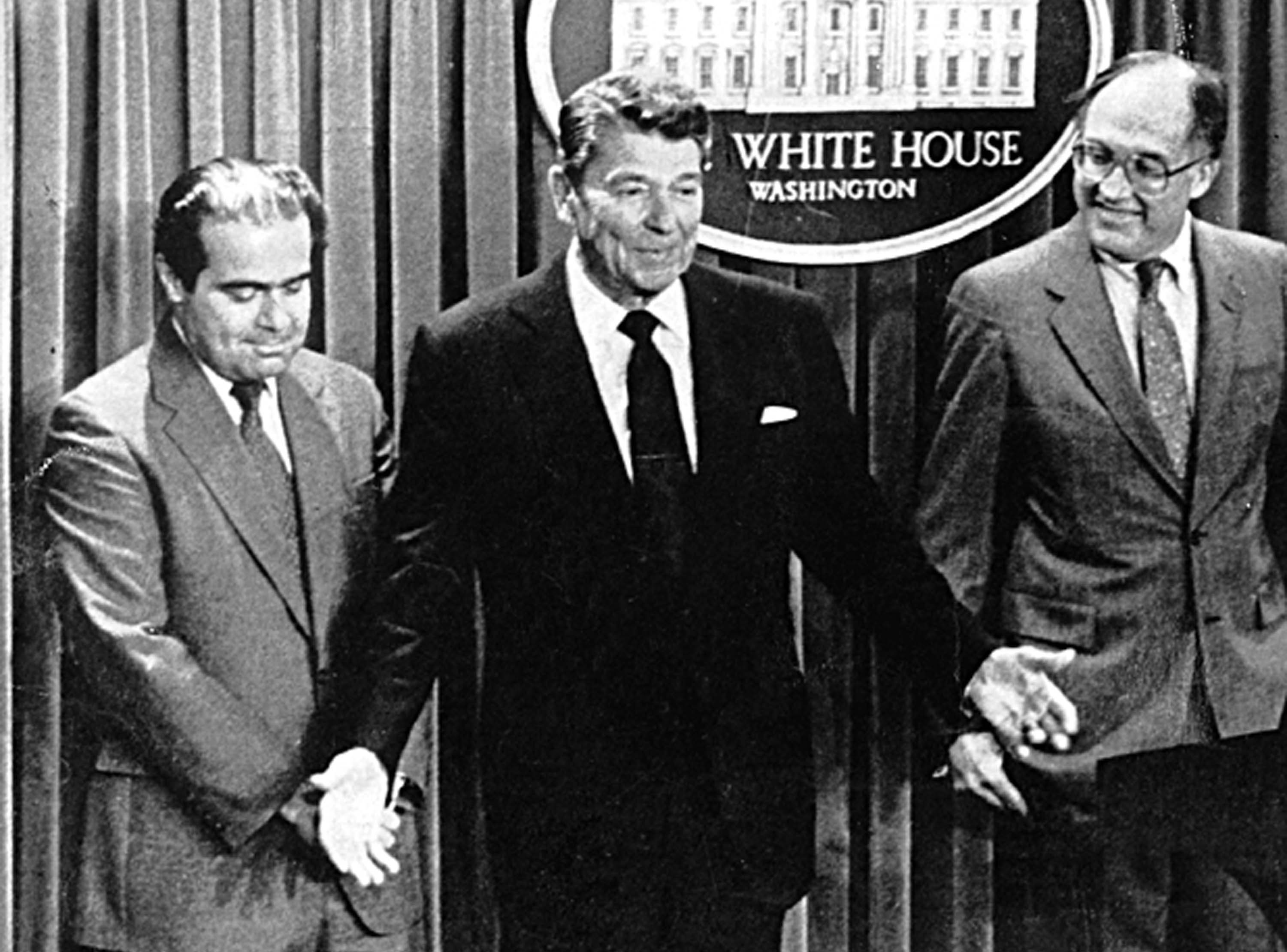 In this 1986 photo shows President Ronald Reagan with Antonin Scalia, left, whom he appointed to fill the Supreme Court post of William H. Rehnquist, right, who was elevated to the position of chief justice, in 1986.