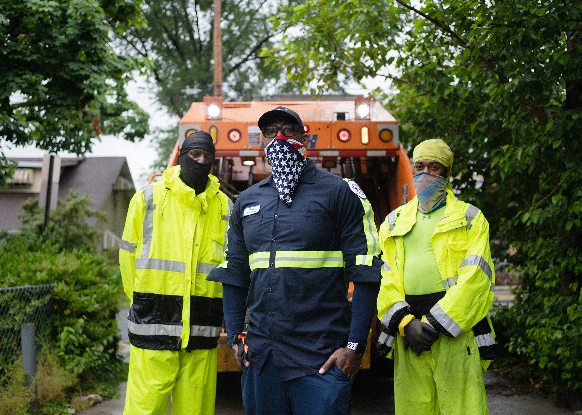 Sanitation Crew Chief, Tavis Clinton, 41, center, and Sanitation Workers, Arvel Baylor, 49, left,  and Maurice Eley, 41, right, stand behind their waste collection vehicle in Southeast Washington, DC.
