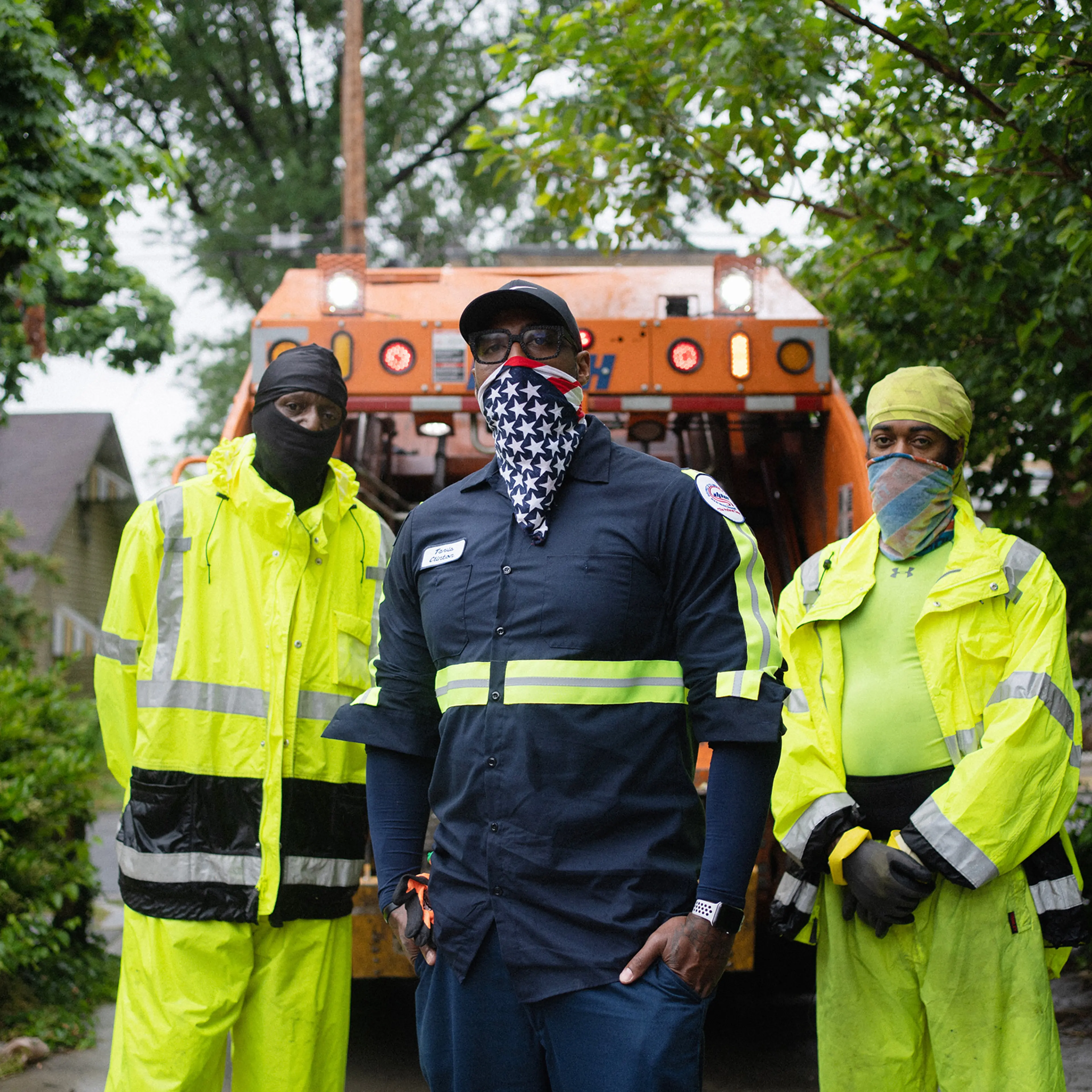 Sanitation Crew Chief, Tavis Clinton, 41, center, and Sanitation Workers, Arvel Baylor, 49, left, and Maurice Eley, 41, right, stand behind their waste collection vehicle in Southeast Washington, DC.