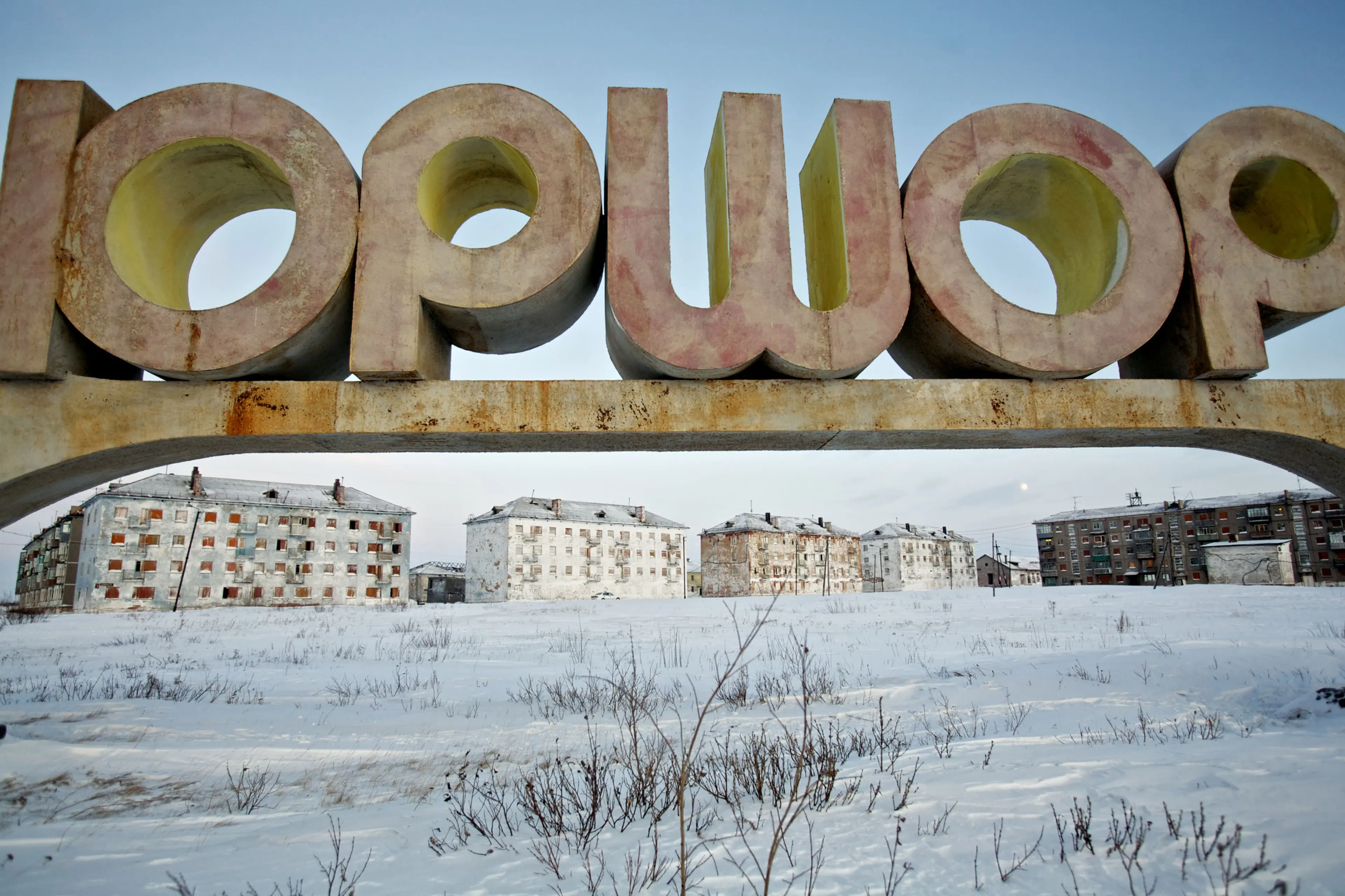 Miner walks past boarded-up apartment block outside Arctic city