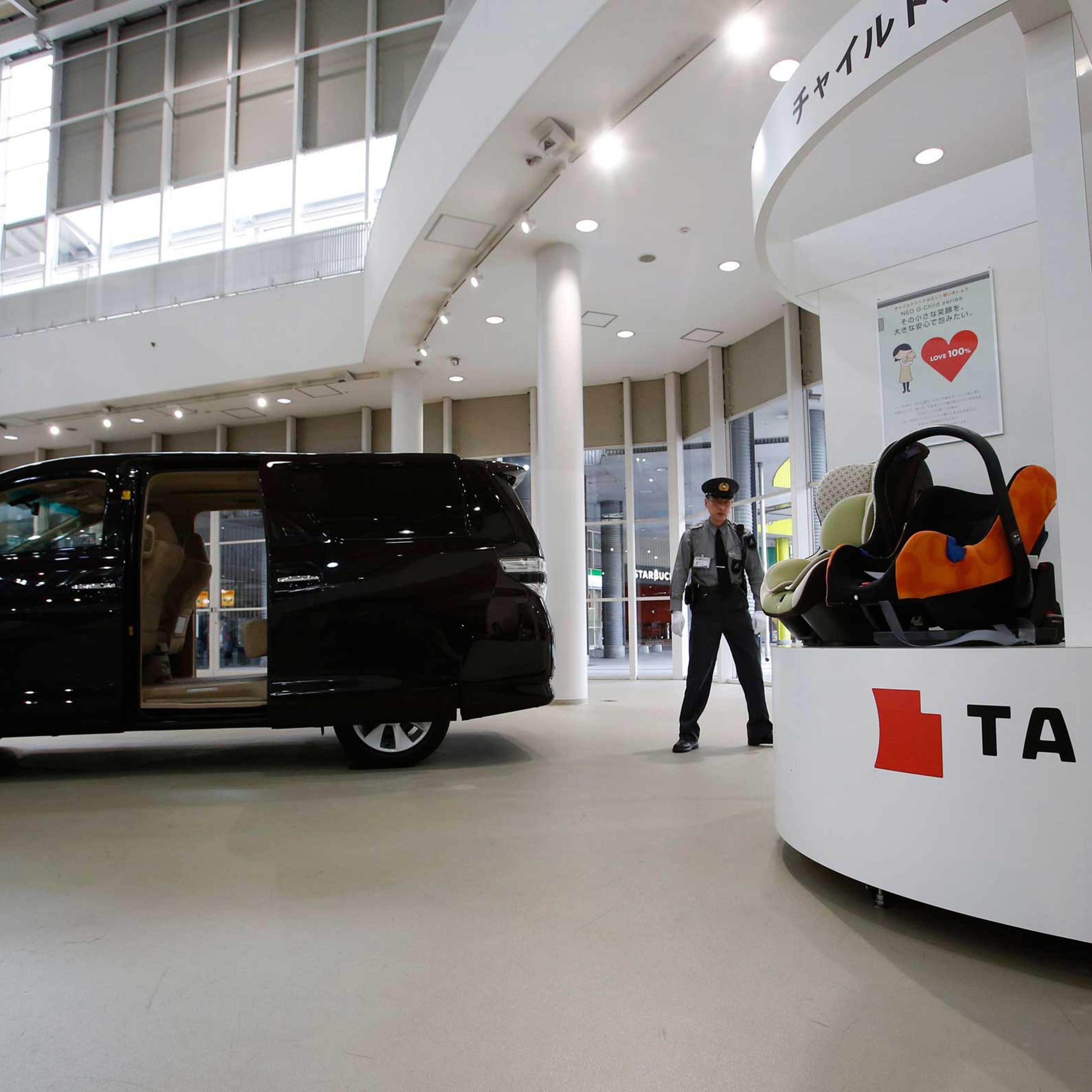 A security guard stands by child seats, manufactured and displayed by Takata Corp. at a Toyota showroom in Tokyo, Nov. 6, 2014.