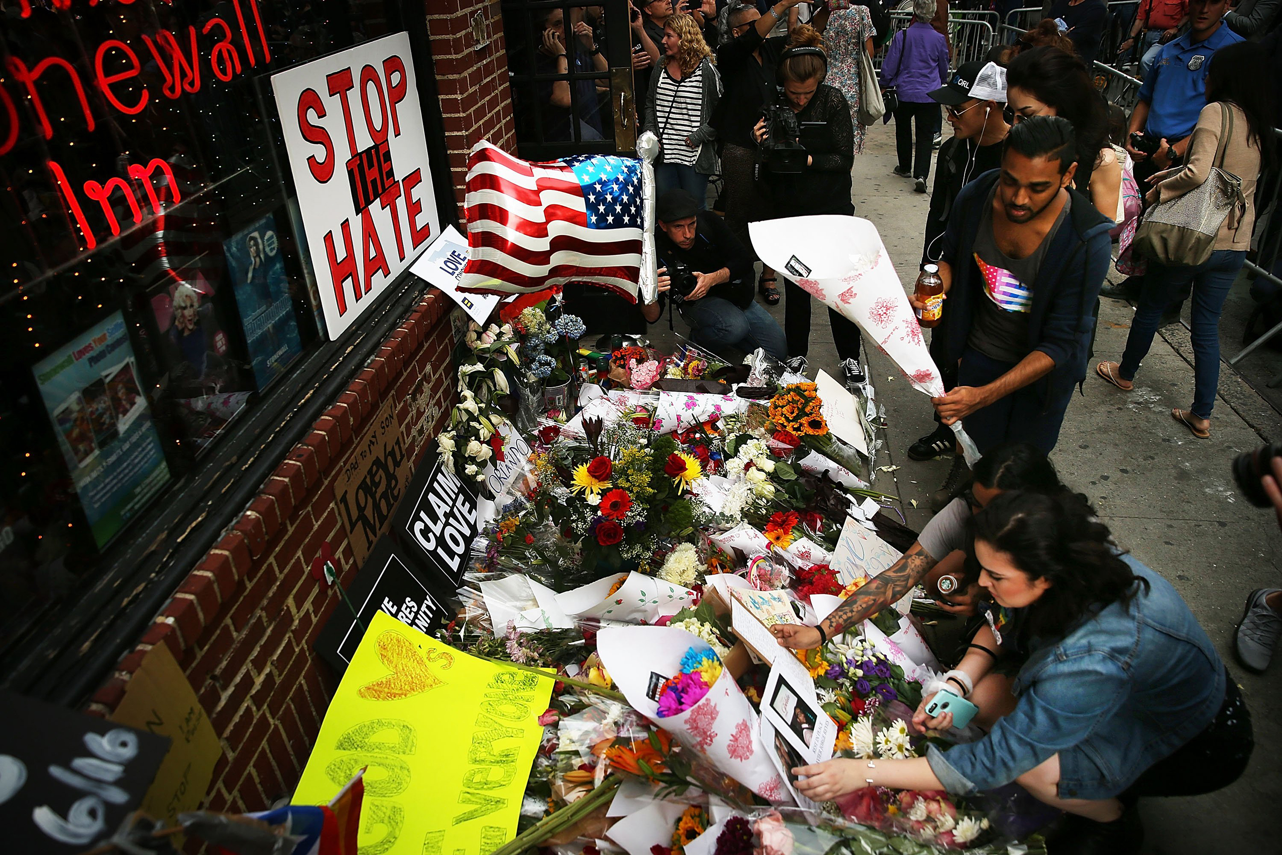People pause in front of the iconic New York City gay and lesbian bar The Stonewall Inn in New York City to lay flowers and grieve for those killed in Orlando on June 13, 2016.