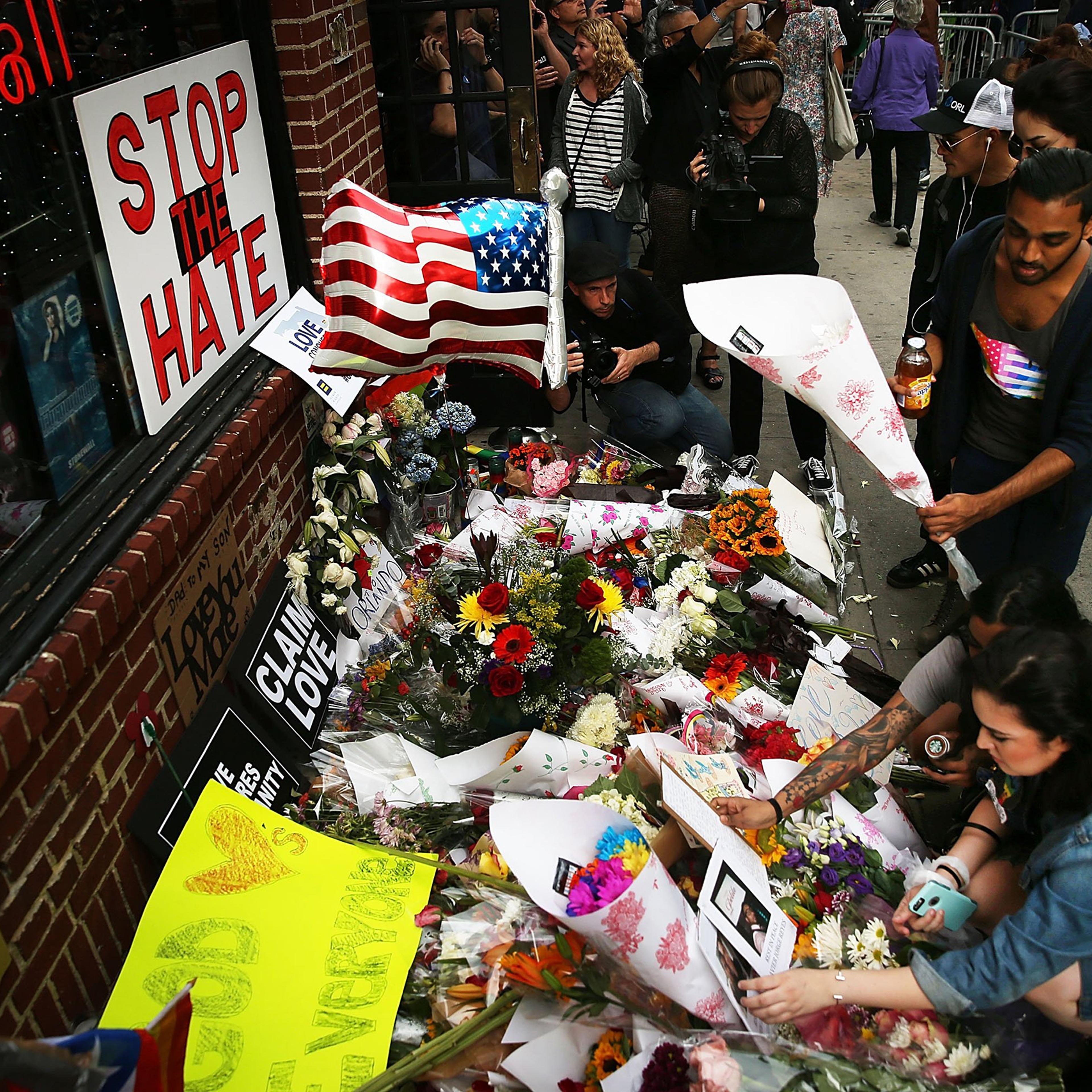 People pause in front of the iconic New York City gay and lesbian bar The Stonewall Inn in New York City to lay flowers and grieve for those killed in Orlando on June 13, 2016.