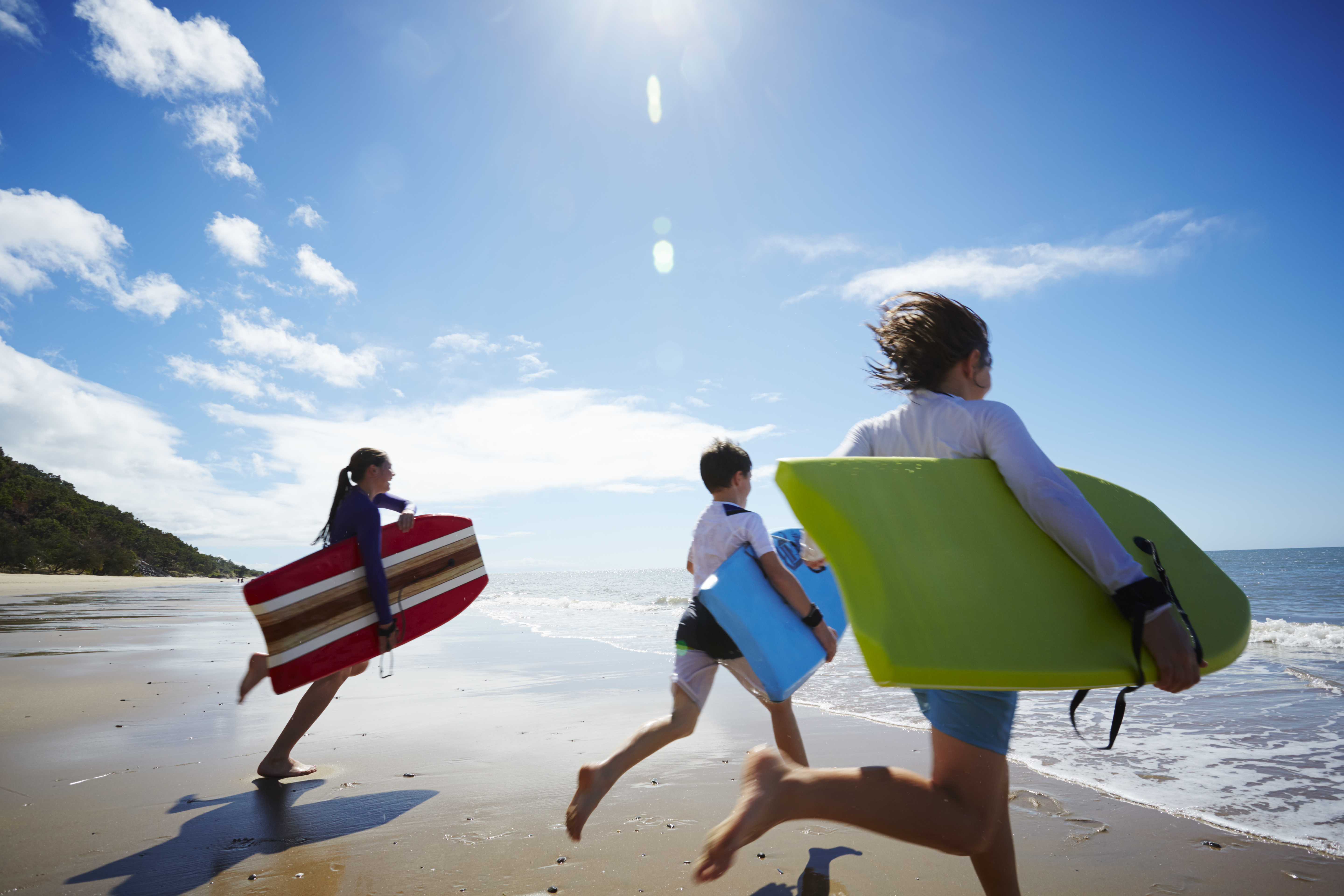 Three children running into the ocean