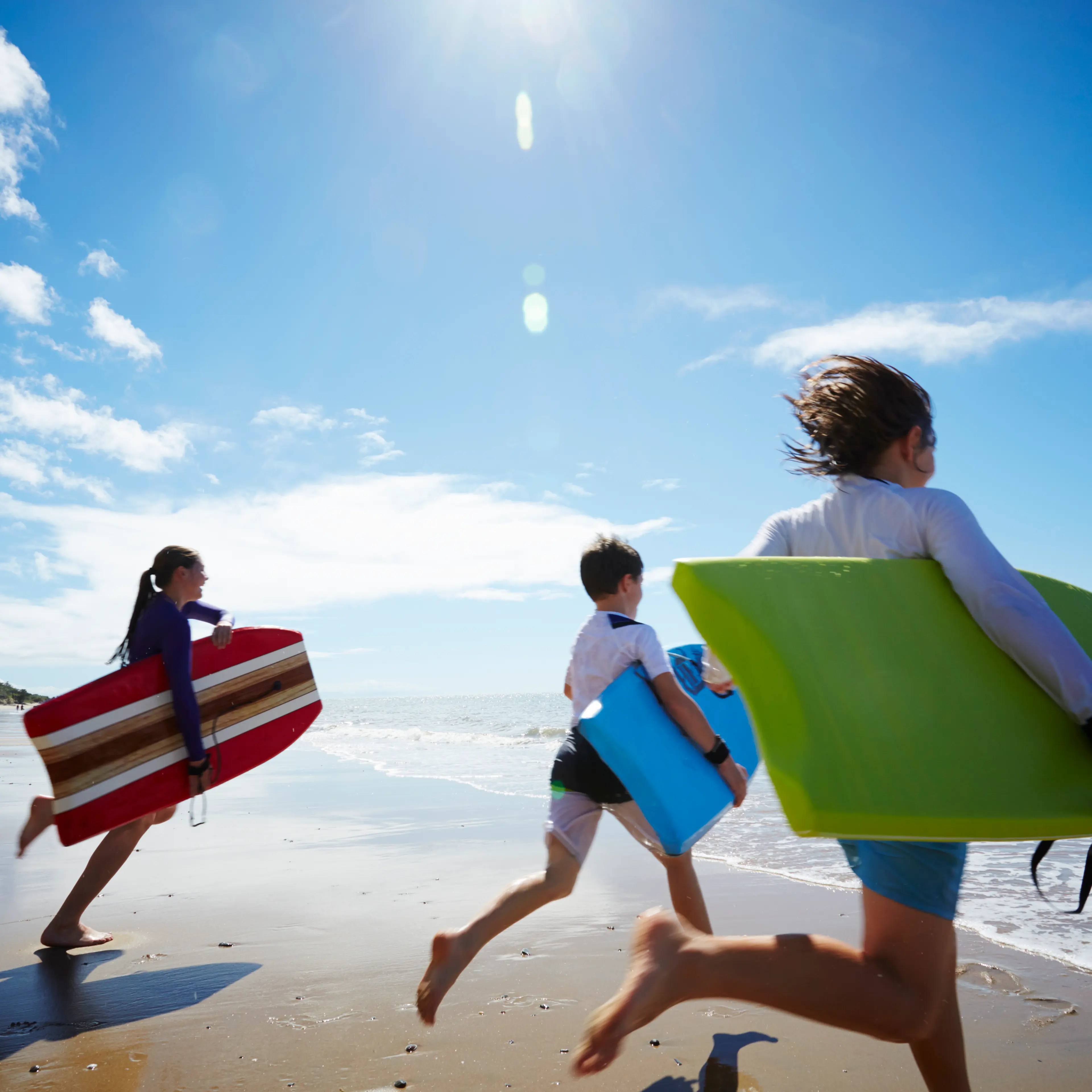 Three children running into the ocean