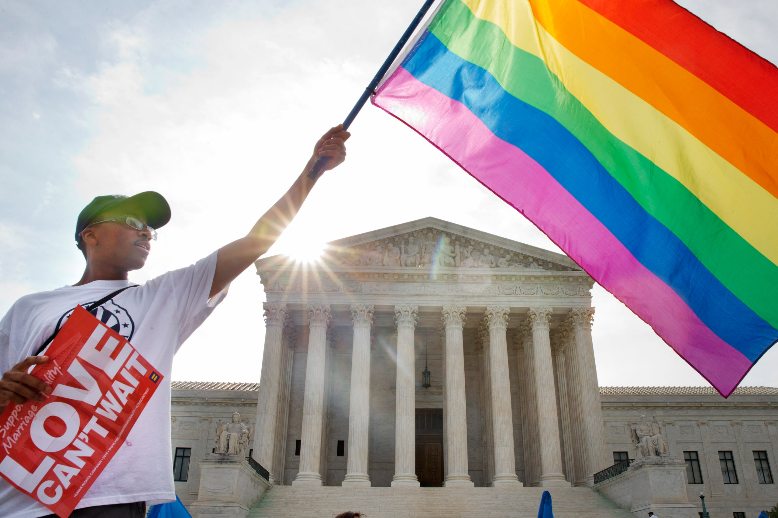 Carlos McKnight of Washington, waves a flag in support of gay marriage outside of the Supreme Court in Washington, Friday June 26, 2015. A major opinion on gay marriage is among the remaining to be released before the term ends at the end of June. (AP Ph