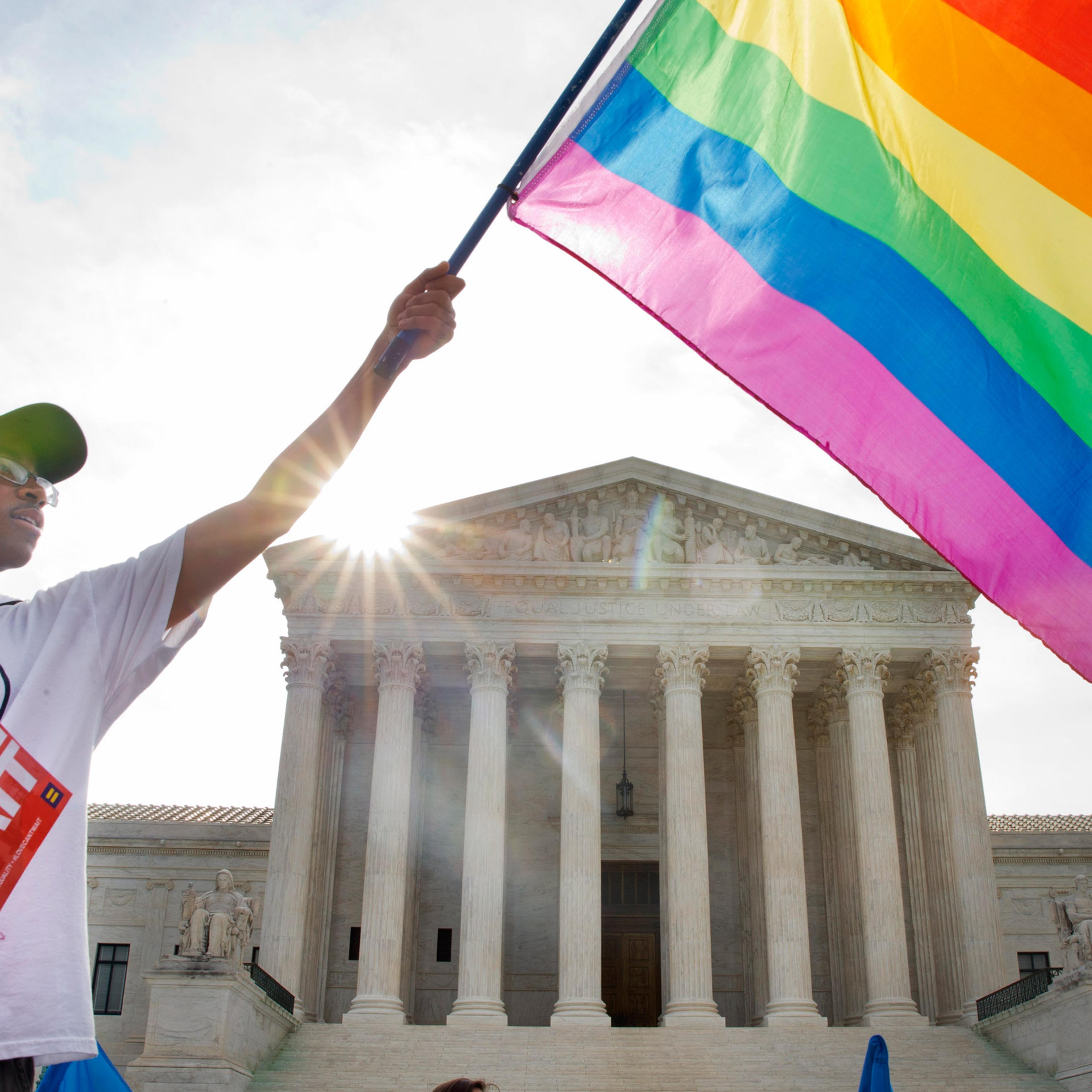 Carlos McKnight of Washington, waves a flag in support of gay marriage outside of the Supreme Court in Washington, Friday June 26, 2015. A major opinion on gay marriage is among the remaining to be released before the term ends at the end of June. (AP Ph