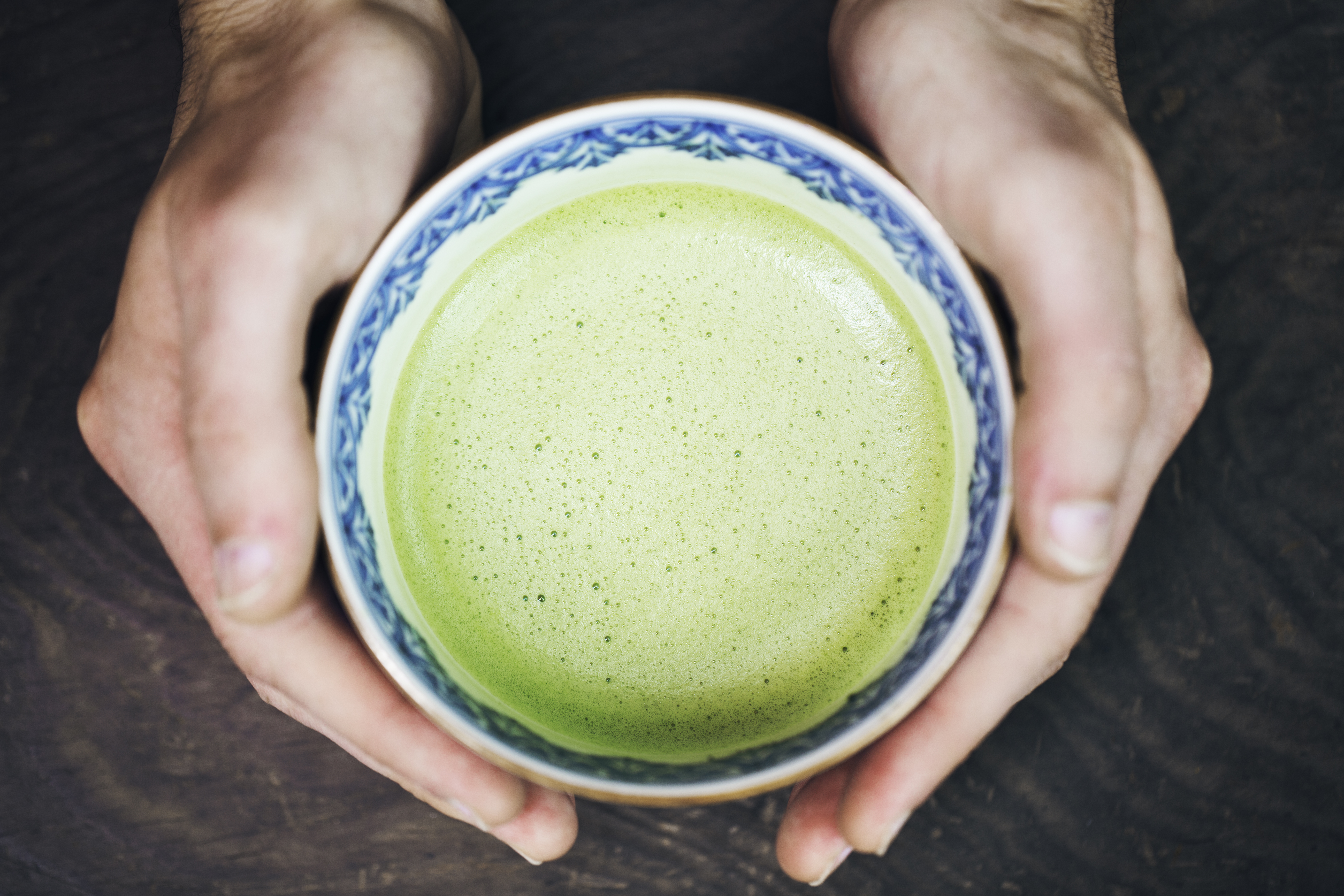 Hands of man holding a cup of Japanese powdered green tea