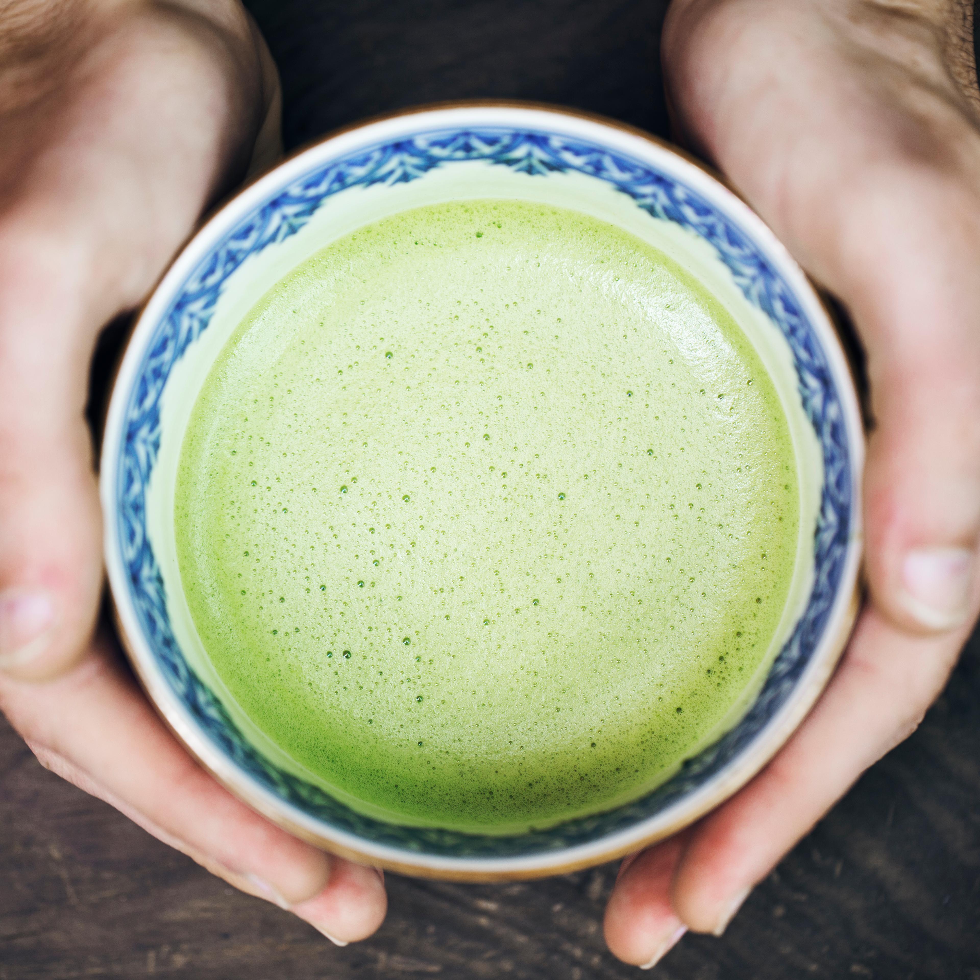 Hands of man holding a cup of Japanese powdered green tea