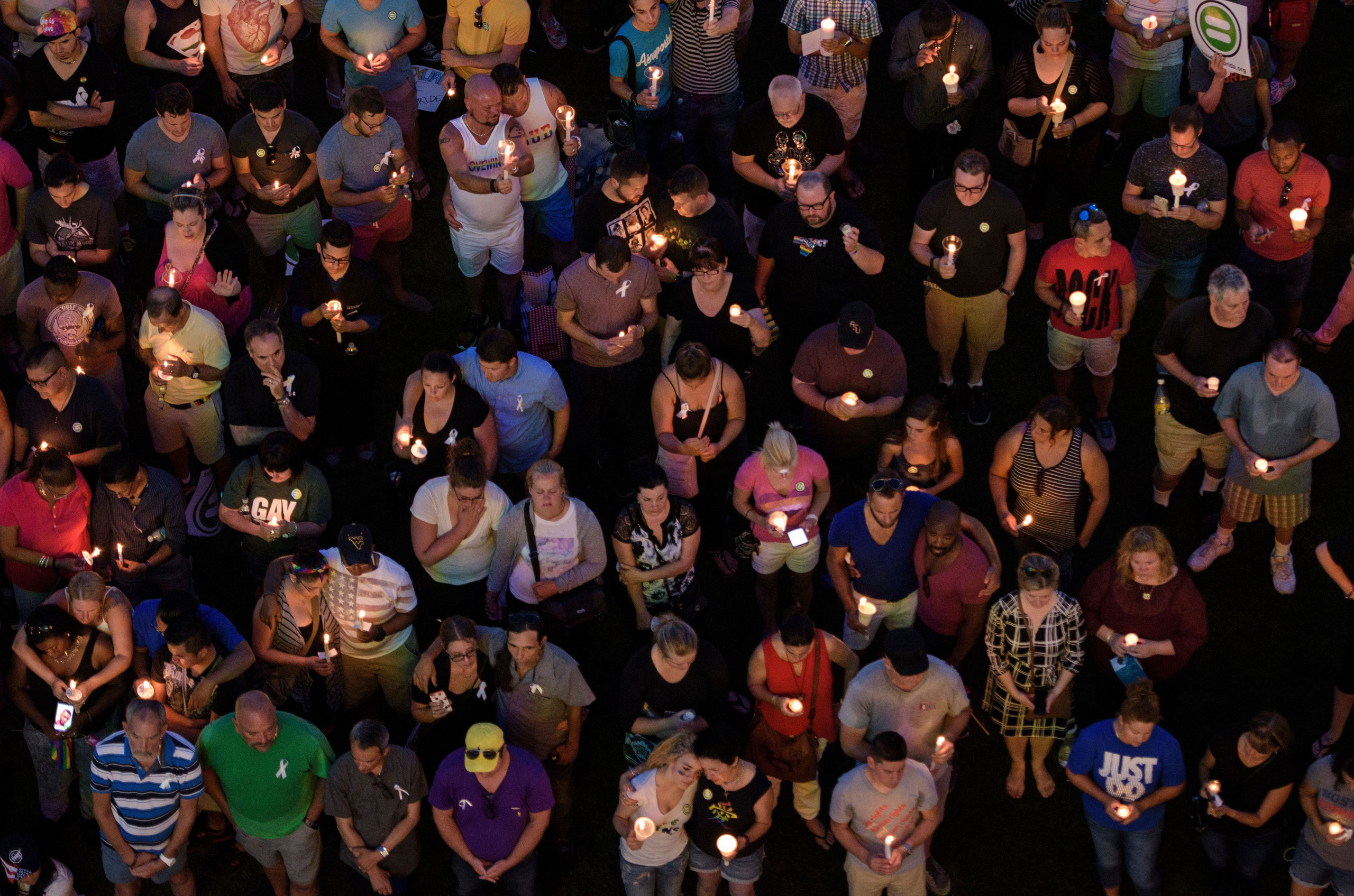 Mourners hold candles while observing a moment of silence during a vigil outside the Dr. Phillips Center for the Performing Arts for the mass shooting victims at the Pulse nightclub in Orlando, Fla.