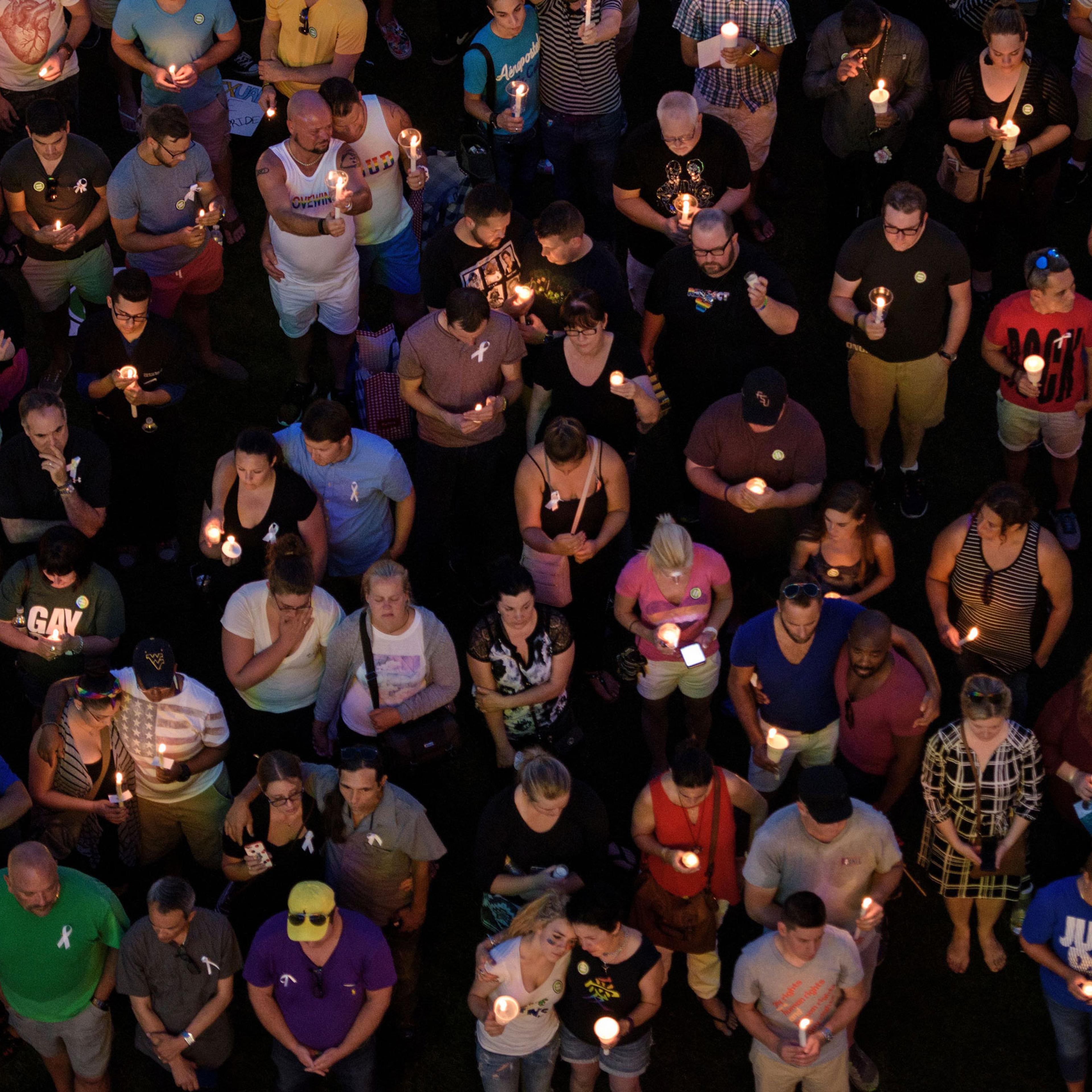 Mourners hold candles while observing a moment of silence during a vigil outside the Dr. Phillips Center for the Performing Arts for the mass shooting victims at the Pulse nightclub in Orlando, Fla.