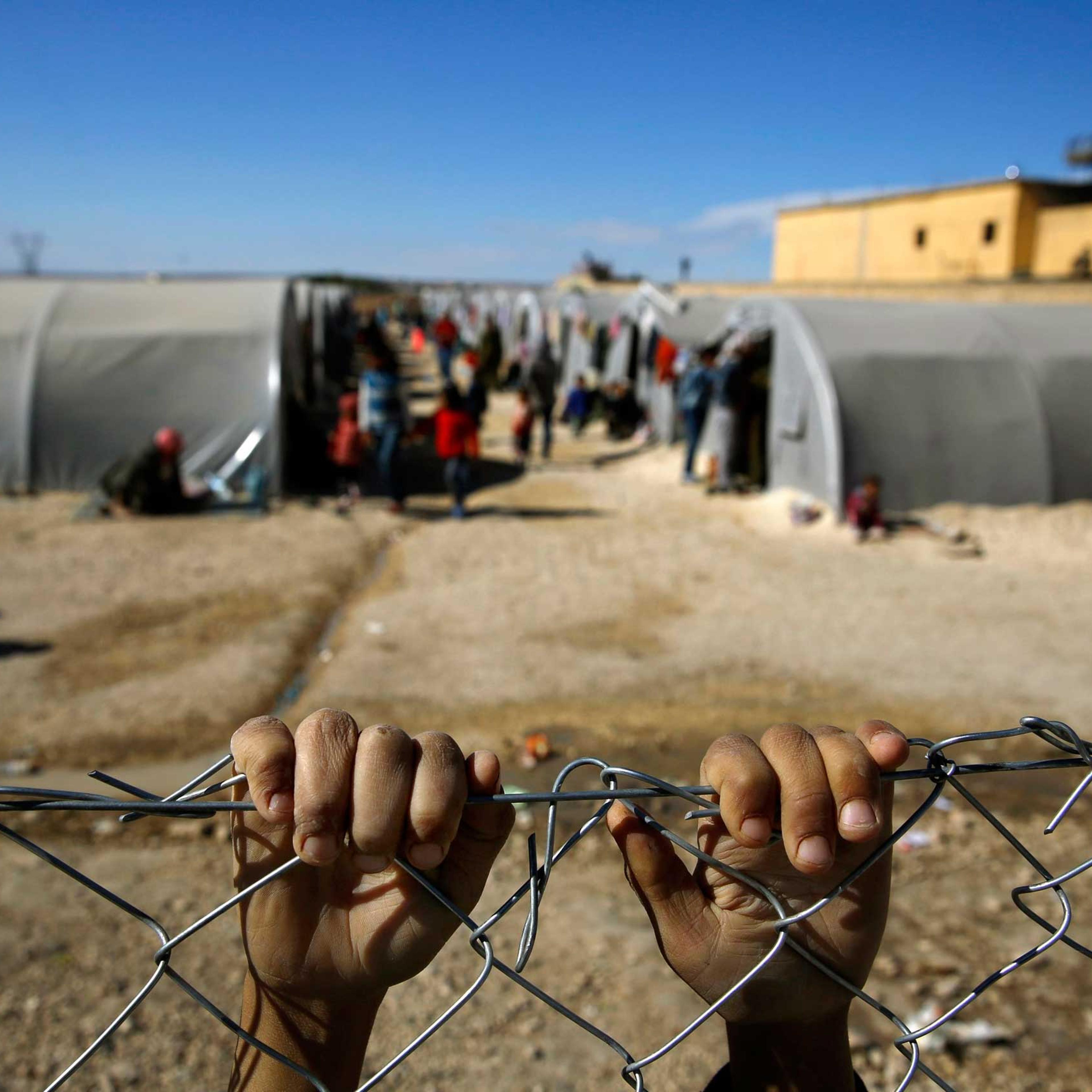 Kurdish refugee boy from the Syrian town of Kobani holds onto a fence that surrounds a refugee camp in the border town of Suruc, Sanliurfa province