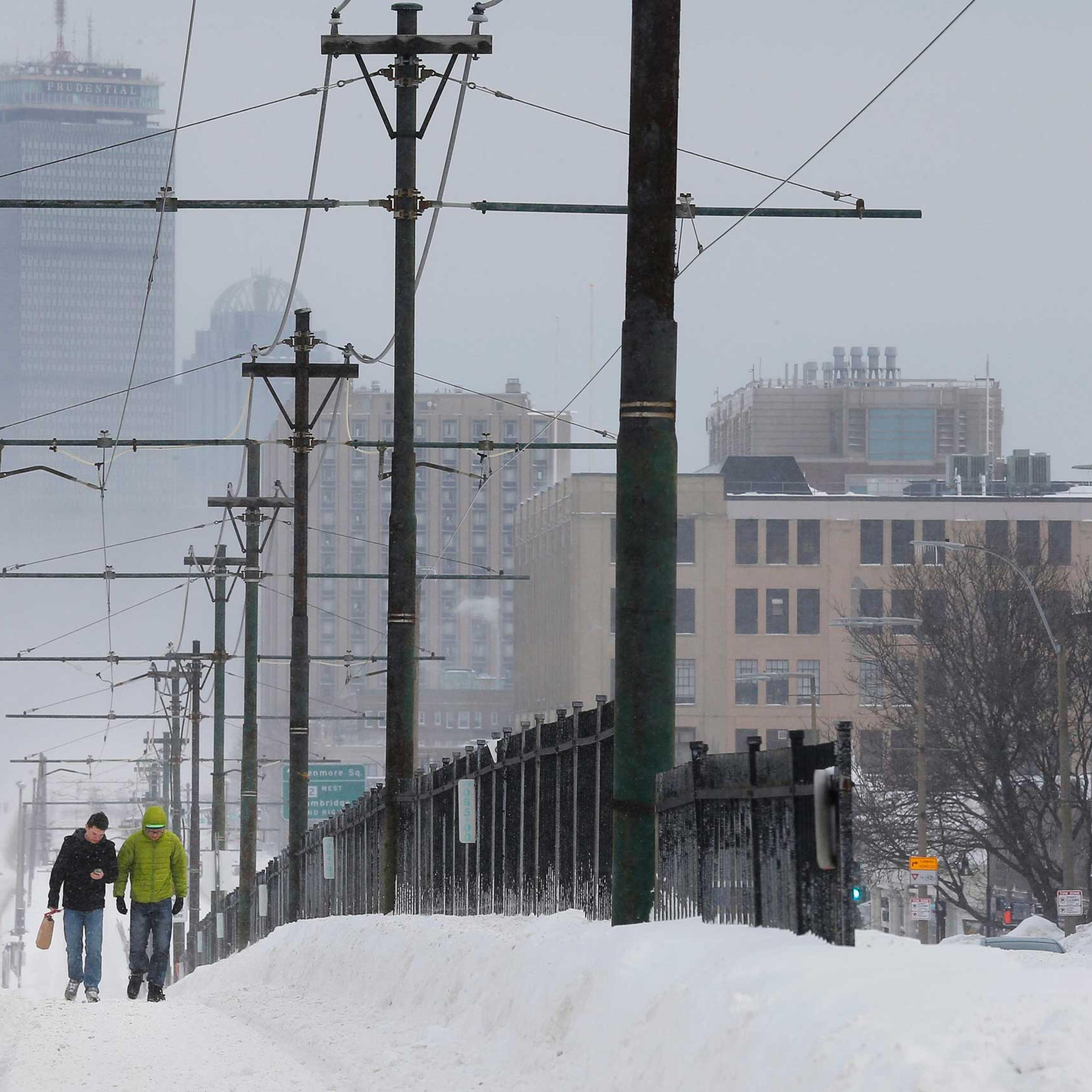 Pedestrians walk along snow covered, MBTA subway rails on Commonwealth Avenue in Boston