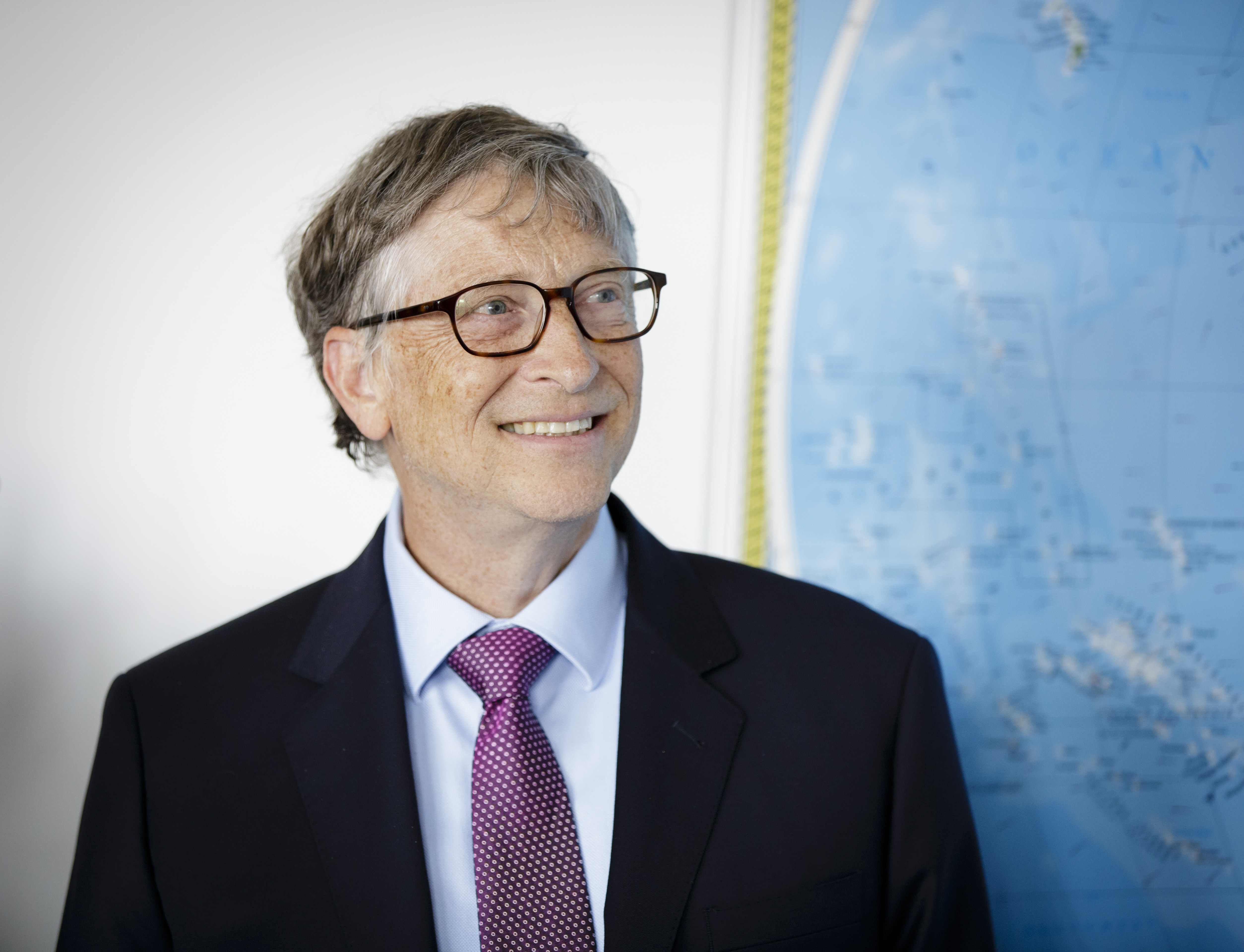 Bill Gates smiling next to map of the world