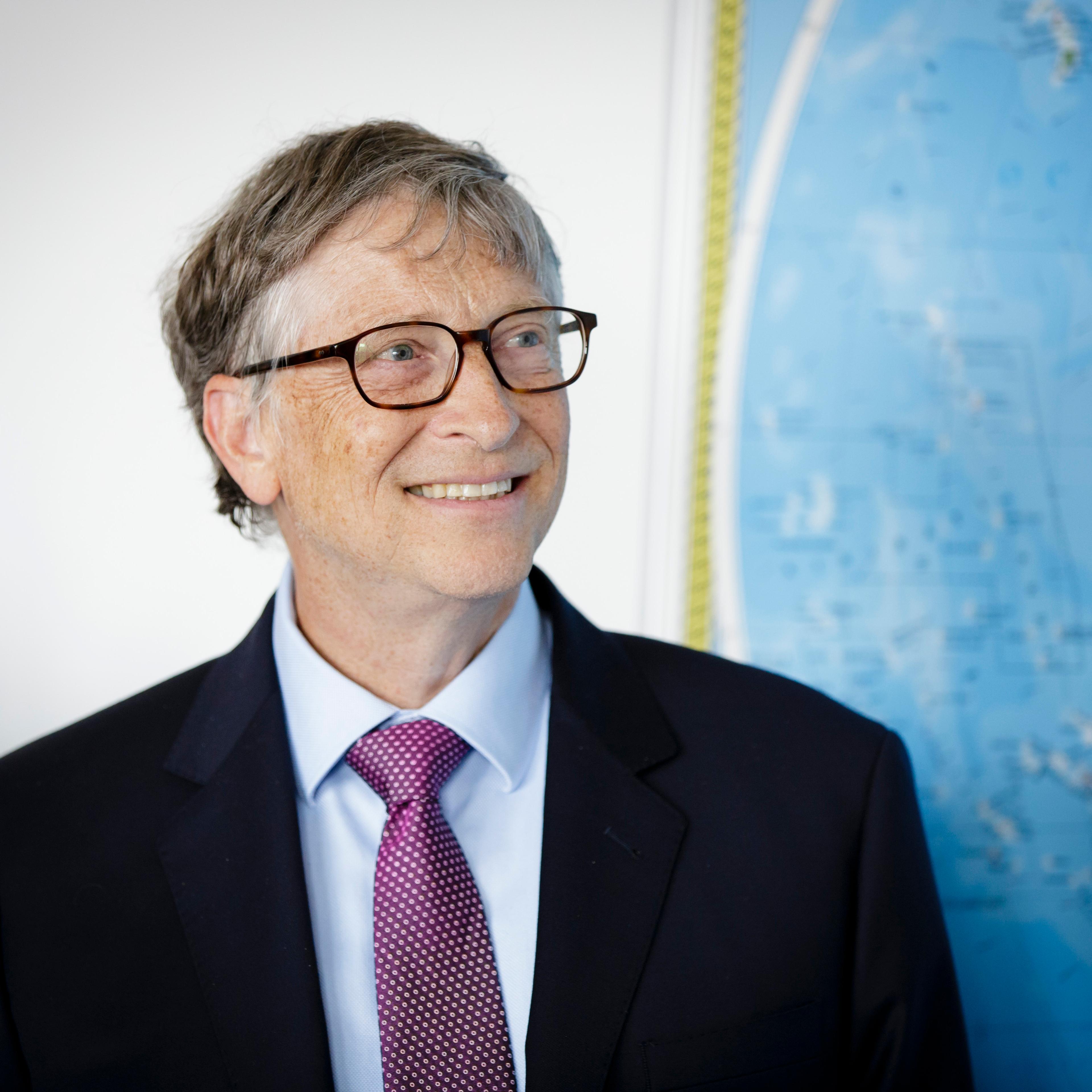 Bill Gates smiling next to map of the world