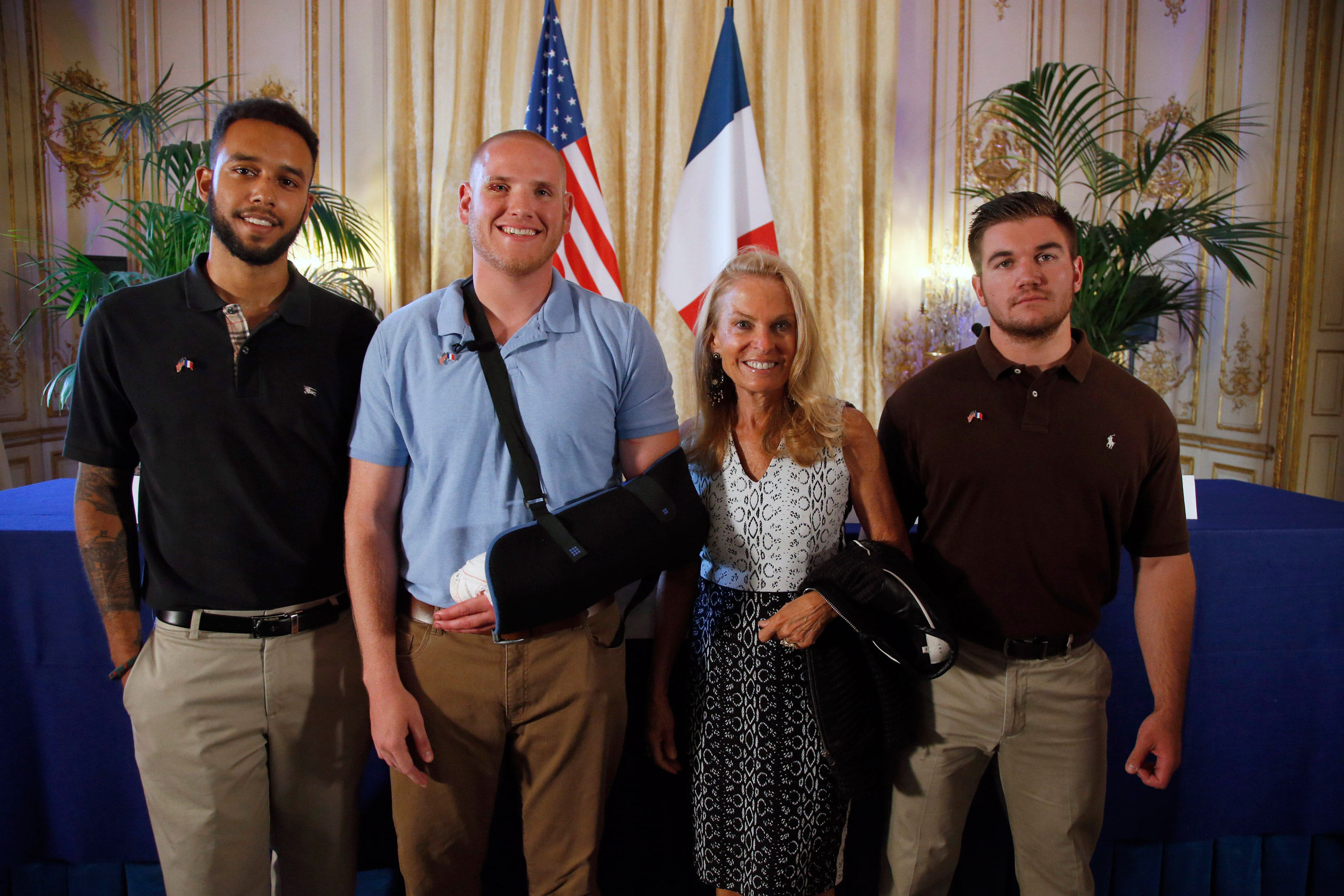 Anthony Sadler, a senior at Sacramento University in California, left, U.S. National Guardsman from Roseburg, Oregon, Alek Skarlatos, right, and U.S. Airman Spencer Stone, second from left, pose for photographers with Jane D. Hartley, U.S. Ambassador to 