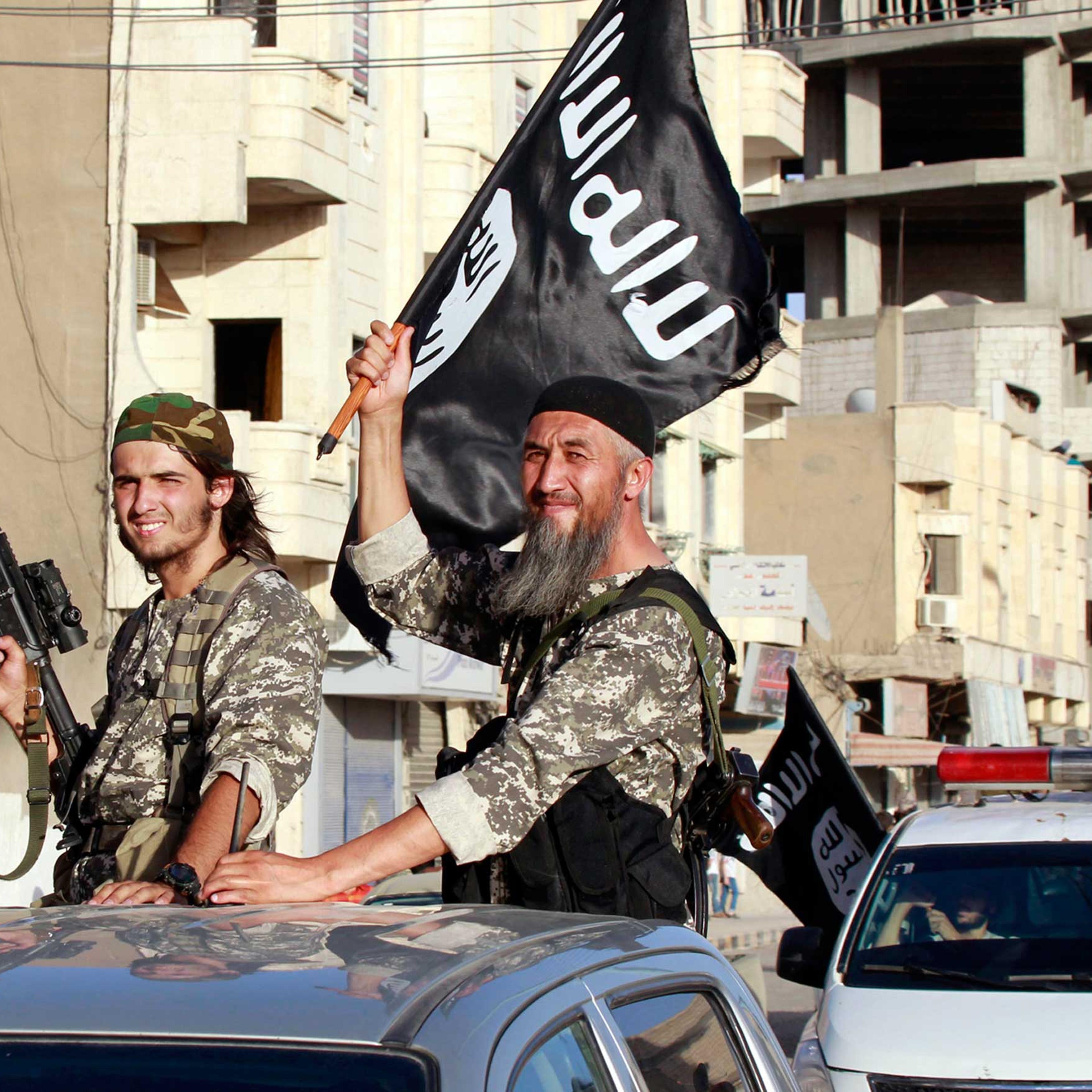 Militant Islamist fighters wave flags as they take part in a military parade along the streets of Syria's northern Raqqa province June 30, 2014.