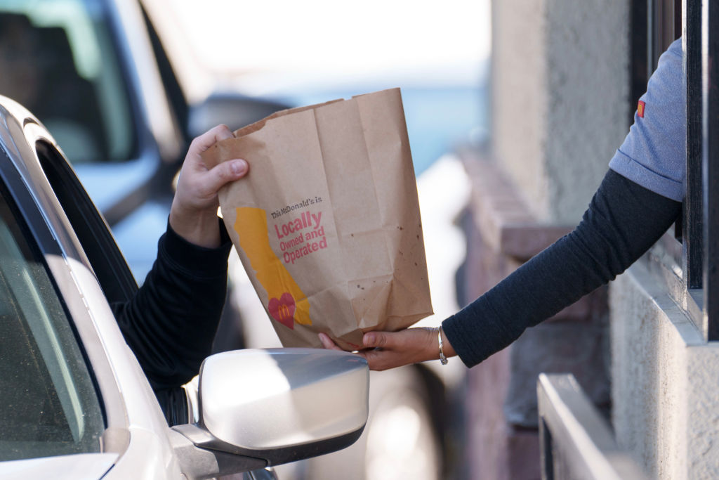 An employee hands a bag to a customer at the drive-thru