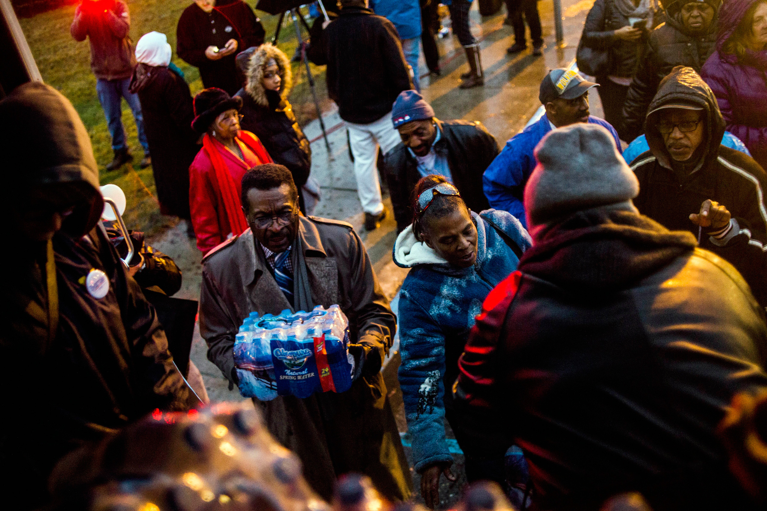 Flint residents line up for free bottled water as activists protest outside of City Hall to protest Michigan Gov. Rick Snyder's handling of the water crisis Friday, Jan. 8, 2016 in Flint. Mich. (Jake May/The Flint Journal-MLive.com via AP) LOCAL TELEVISI