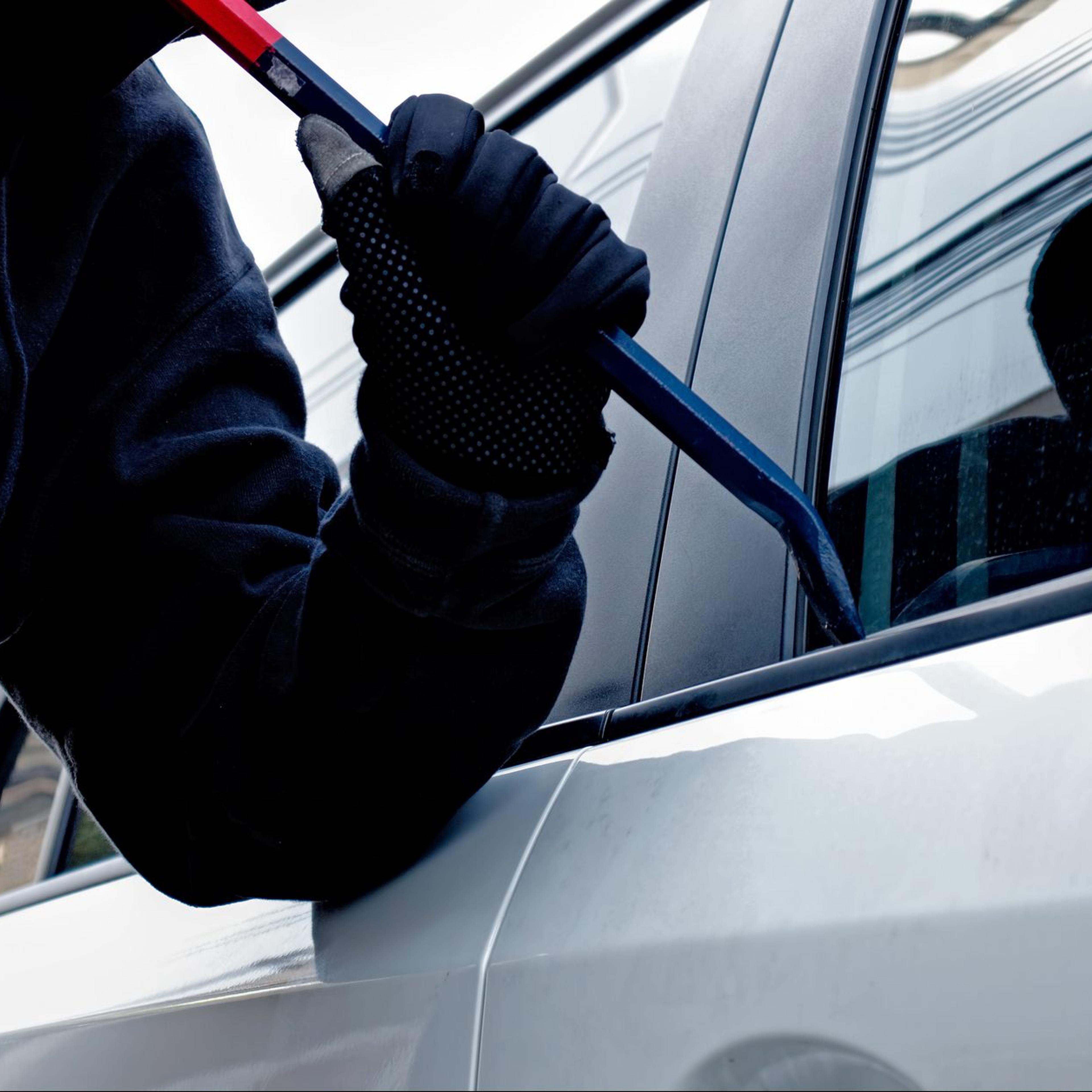 Masked burglar trying to get into a car