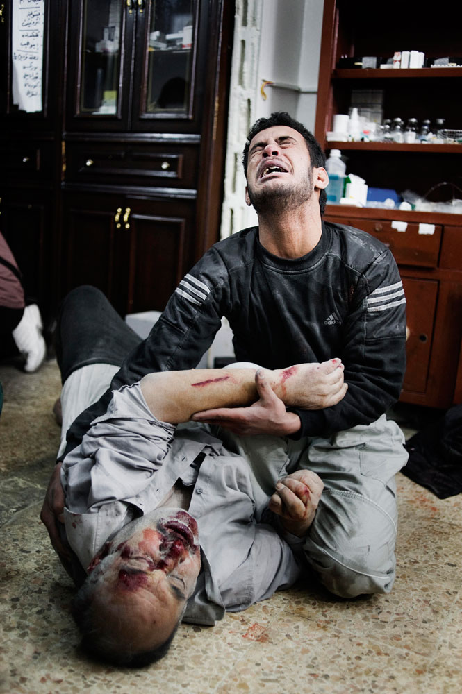A Syrian man holds his wounded brother in a house that is used as a hospital in Bab Amr, a southern neighborhood of Homs. Feb. 6, 2012