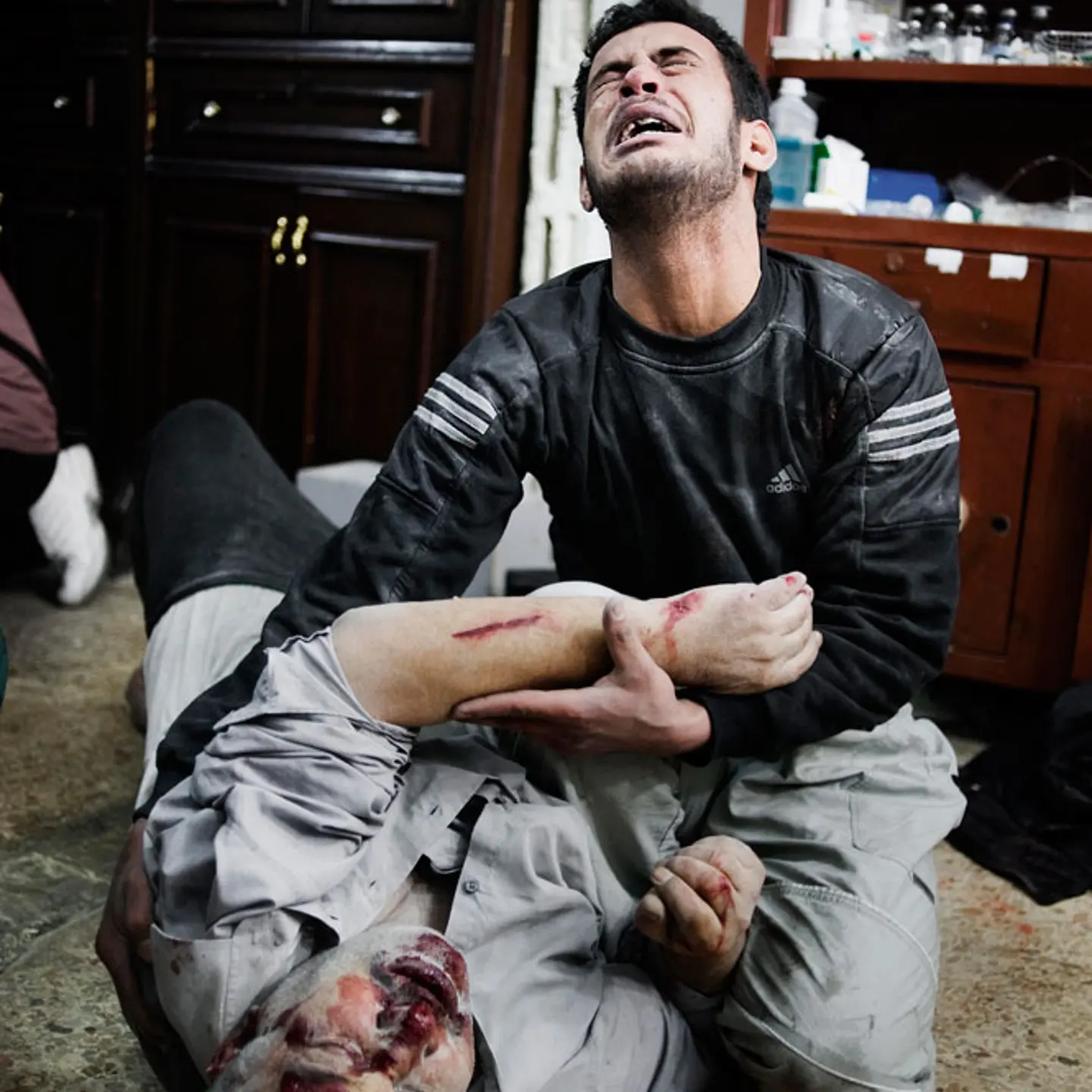 A Syrian man holds his wounded brother in a house that is used as a hospital in Bab Amr, a southern neighborhood of Homs. Feb. 6, 2012