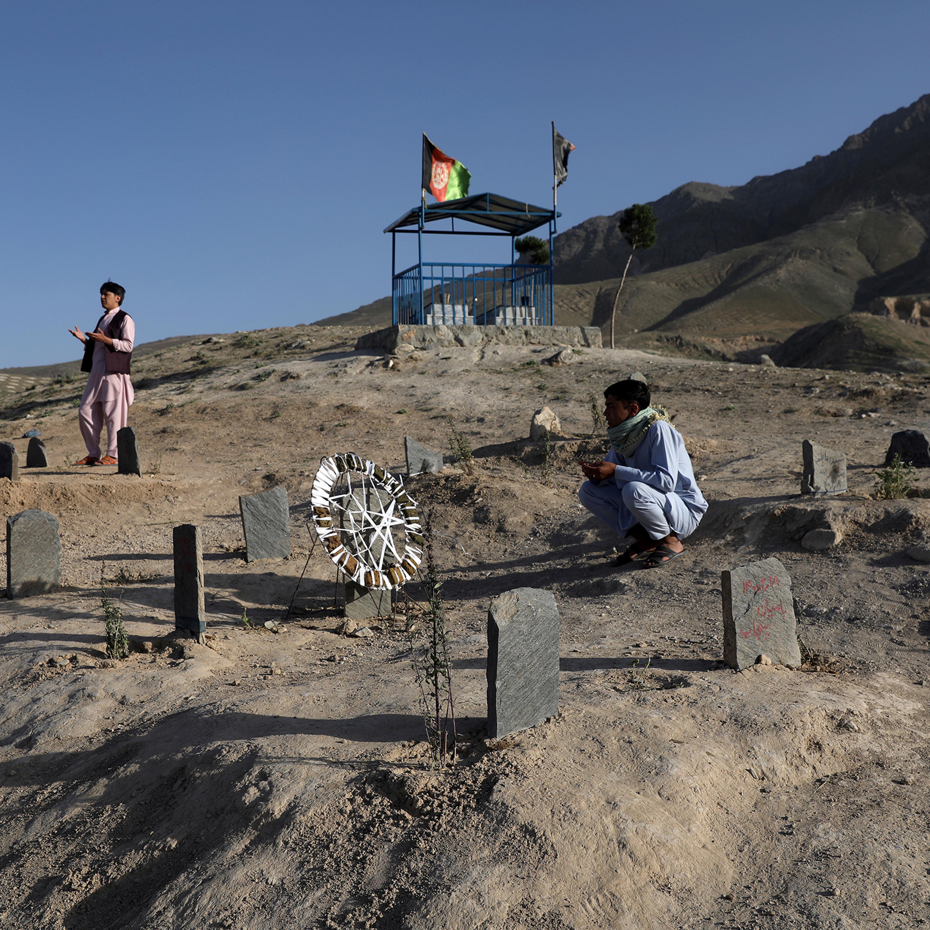 Afghan men pray near the grave of relatives, who were killed in the May bombings near Syed Al-Shahada girls school, at a cemetery on the outskirts of Kabul on June 2, 2021.